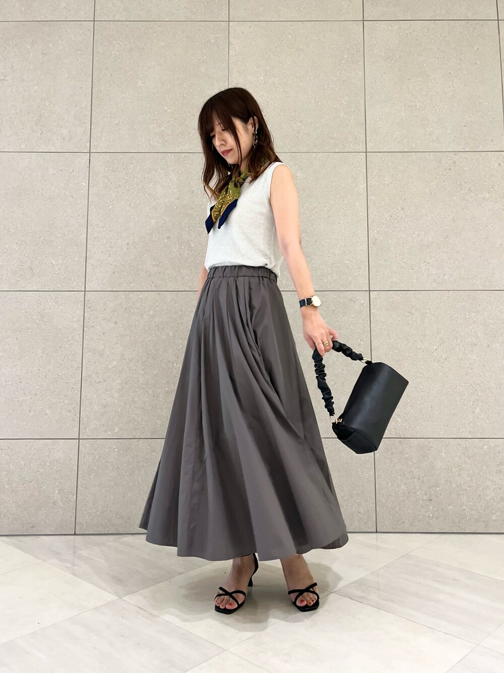 シルバー系のニット/セーター、グレー系のスカート、ブラック系のハンドバッグを着用したレディースの夏コーディネートの2枚目の写真