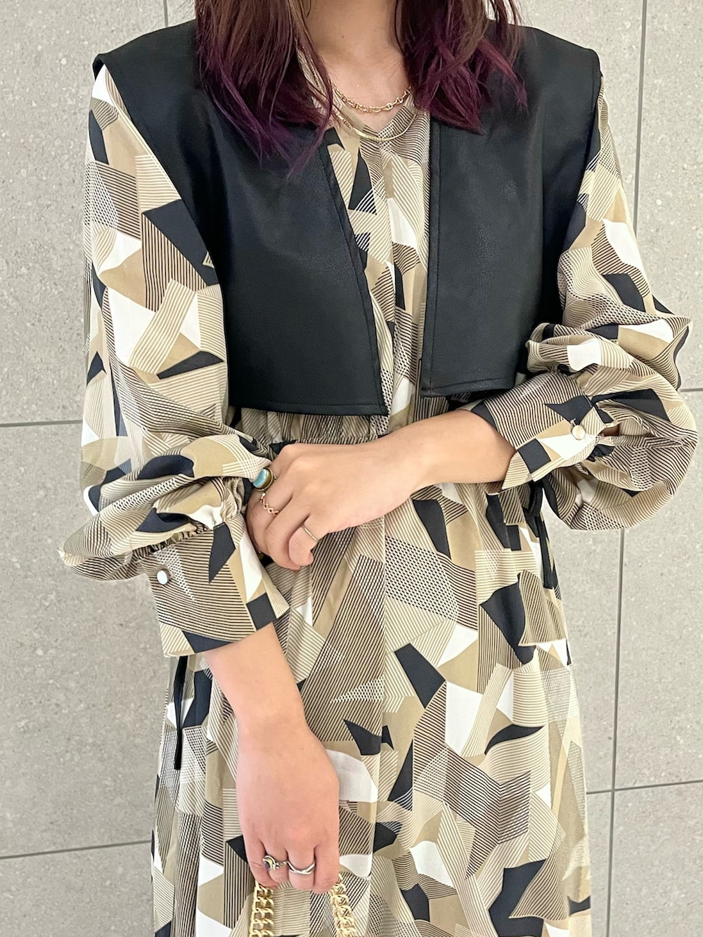 ベージュ系のワンピース、ブラック系のベスト、ブラック系のハンドバッグを着用したレディースの秋コーディネートの3枚目の写真