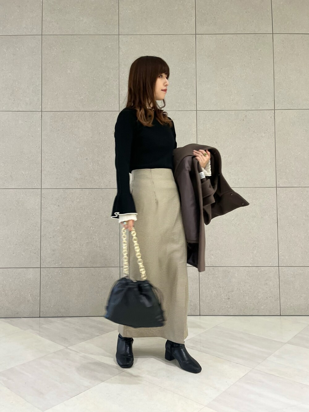 ブラウン系のその他アウター、ブラック系のニット/セーター、ベージュ系のスカートを着用したレディースの冬コーディネートの3枚目の写真