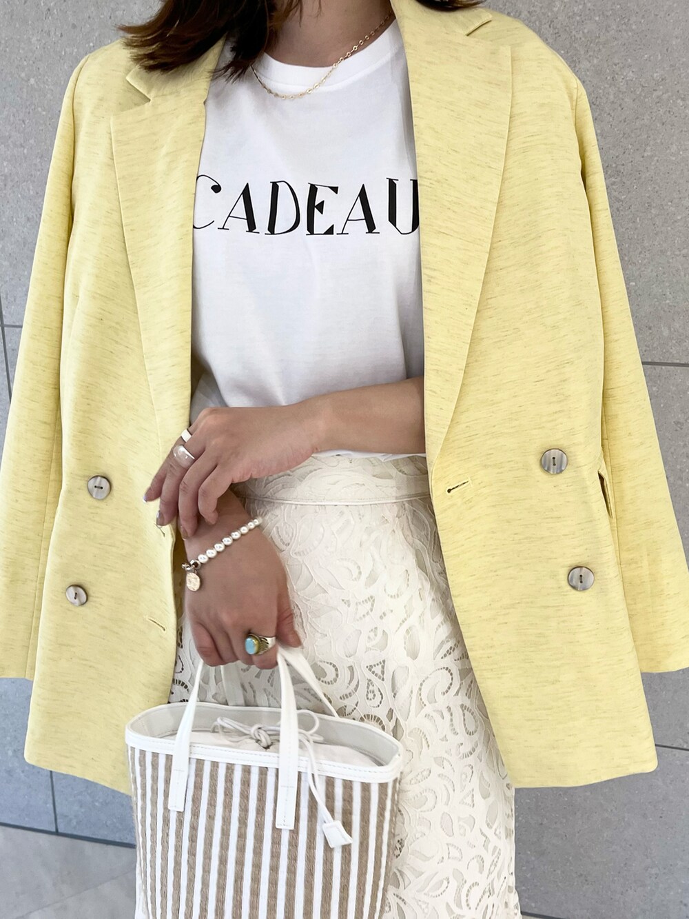 イエロー系のノーカラージャケット、ホワイト系のTシャツ/カットソー、ホワイト系のハンドバッグを着用したレディースの春コーディネートの4枚目の写真