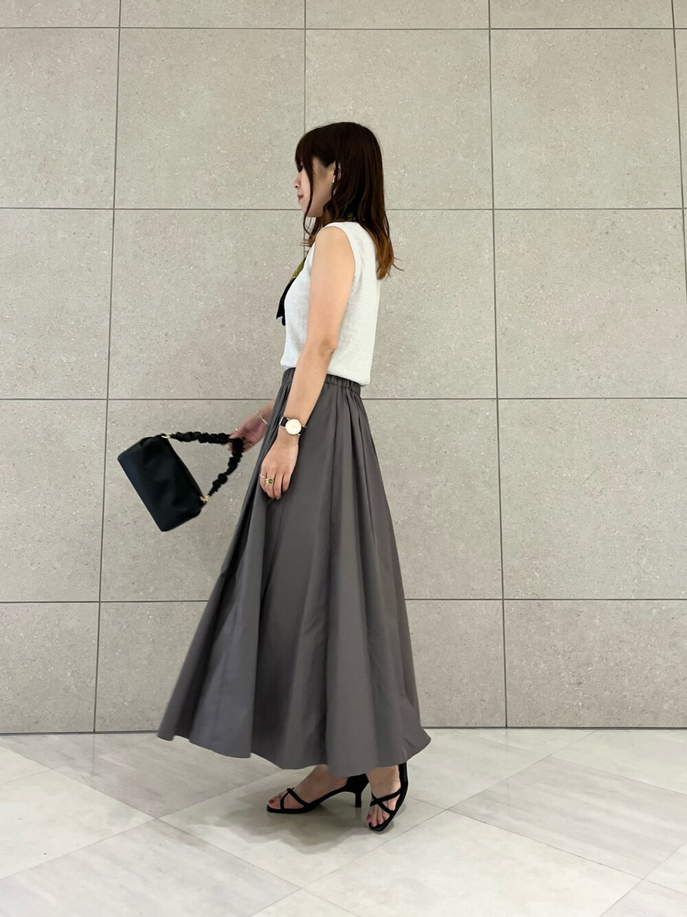 シルバー系のニット/セーター、グレー系のスカート、ブラック系のハンドバッグを着用したレディースの夏コーディネートの3枚目の写真