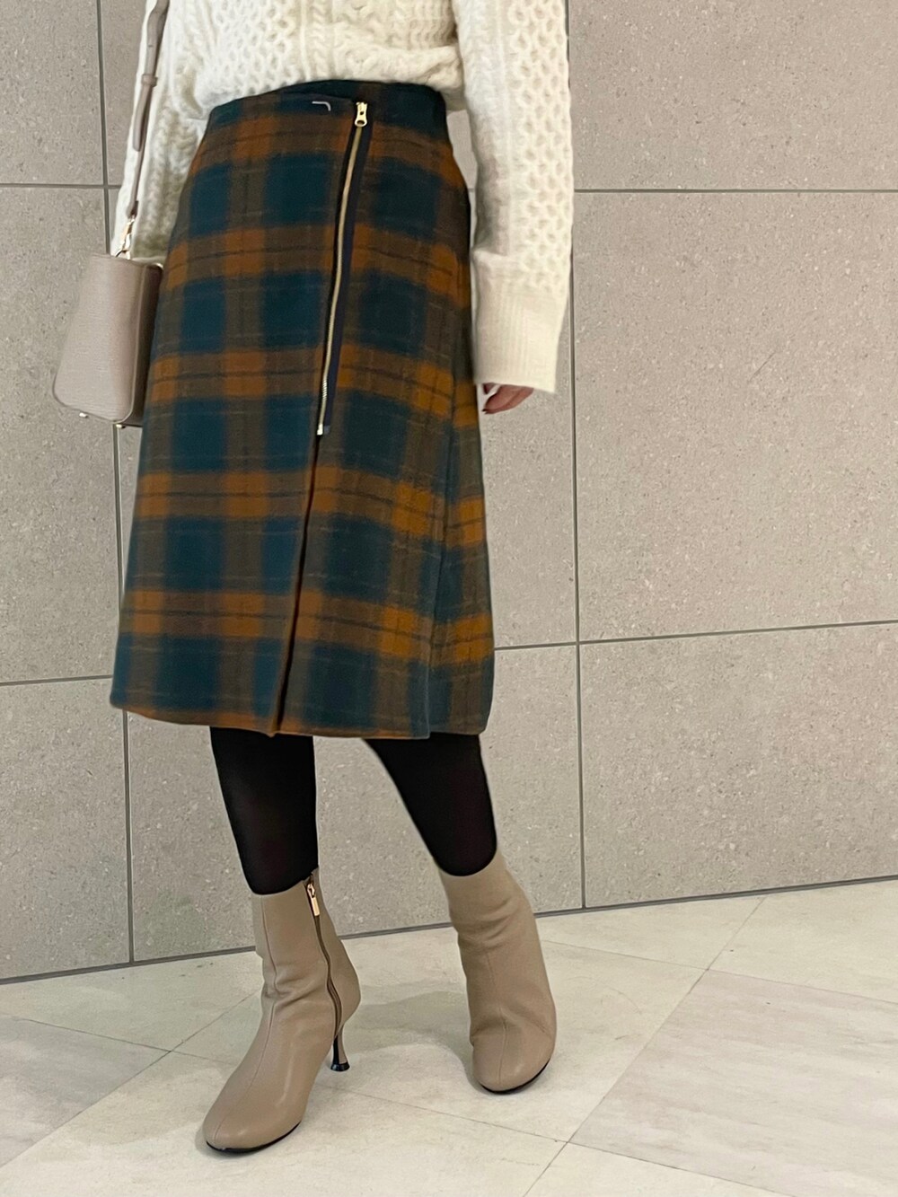 ブラウン系のブーツ、ホワイト系のニット/セーター、オレンジ系のスカートを着用したレディースの秋コーディネートの5枚目の写真