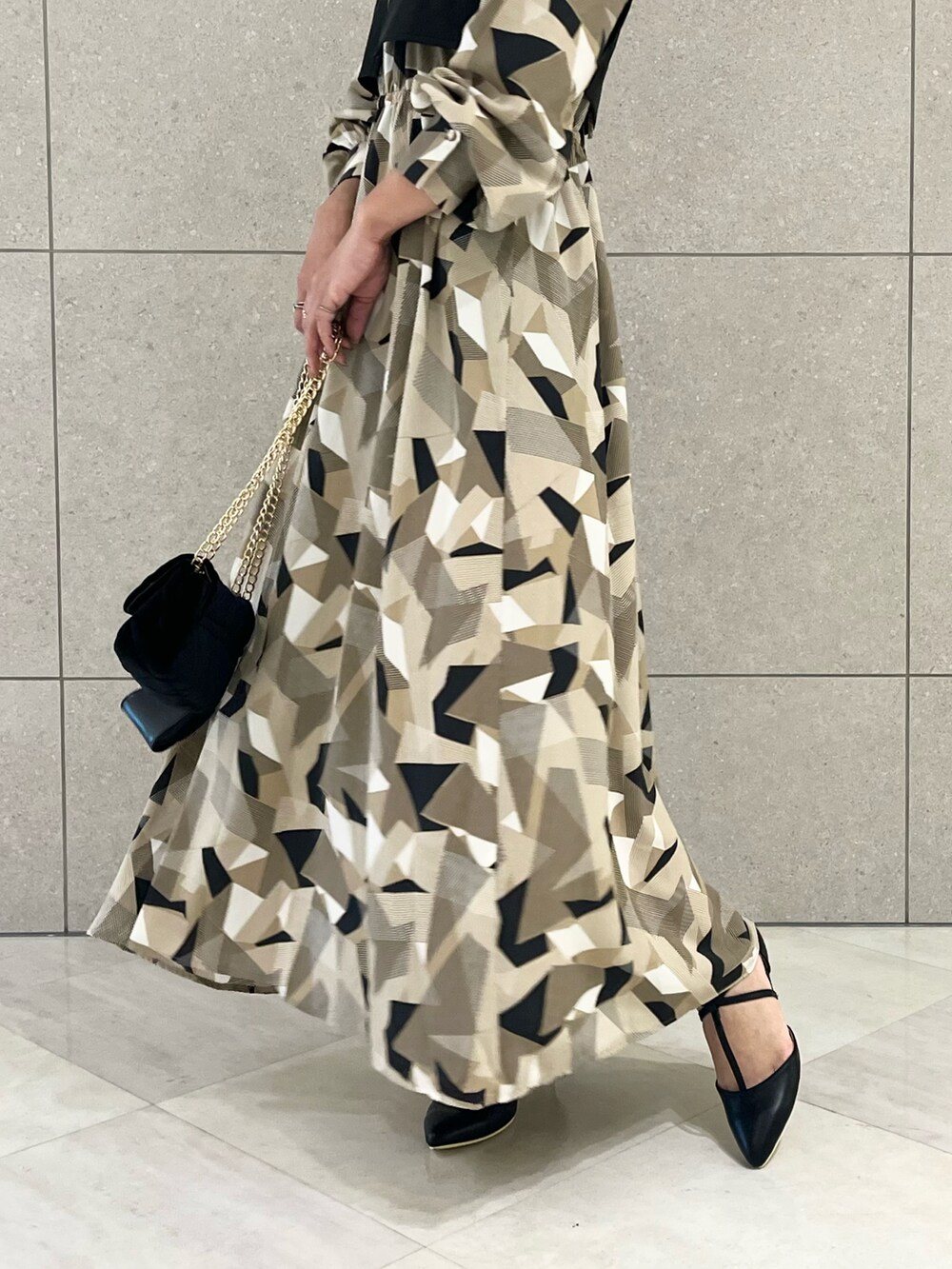 ベージュ系のワンピース、ブラック系のベスト、ブラック系のハンドバッグを着用したレディースの秋コーディネートの5枚目の写真