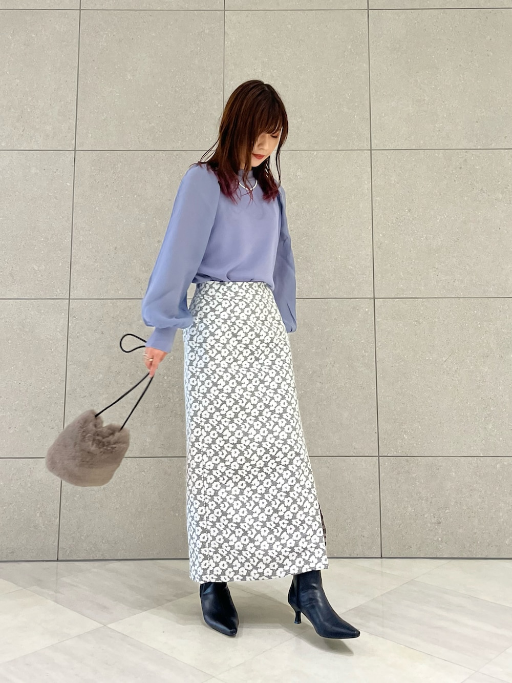 ブルー系のニット/セーター、グレー系のスカート、ブラウン系のハンドバッグを着用したレディースの秋コーディネートの2枚目の写真
