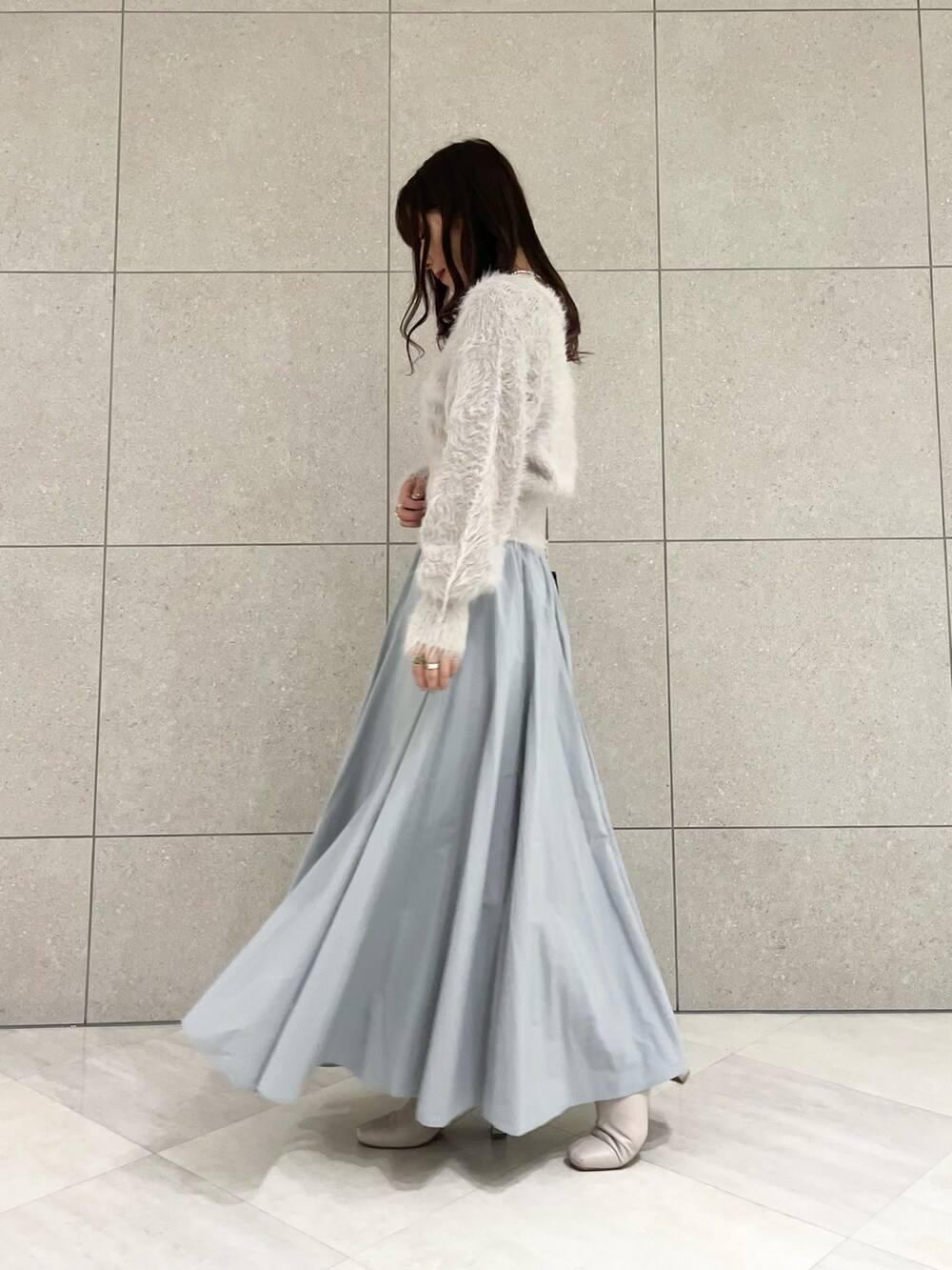 グレー系のカーディガン/ボレロ、グリーン系のハンドバッグ、ブルー系のスカートを着用したレディースの冬コーディネートの2枚目の写真