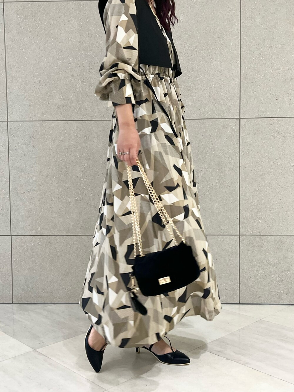 ベージュ系のワンピース、ブラック系のベスト、ブラック系のハンドバッグを着用したレディースの秋コーディネートの4枚目の写真