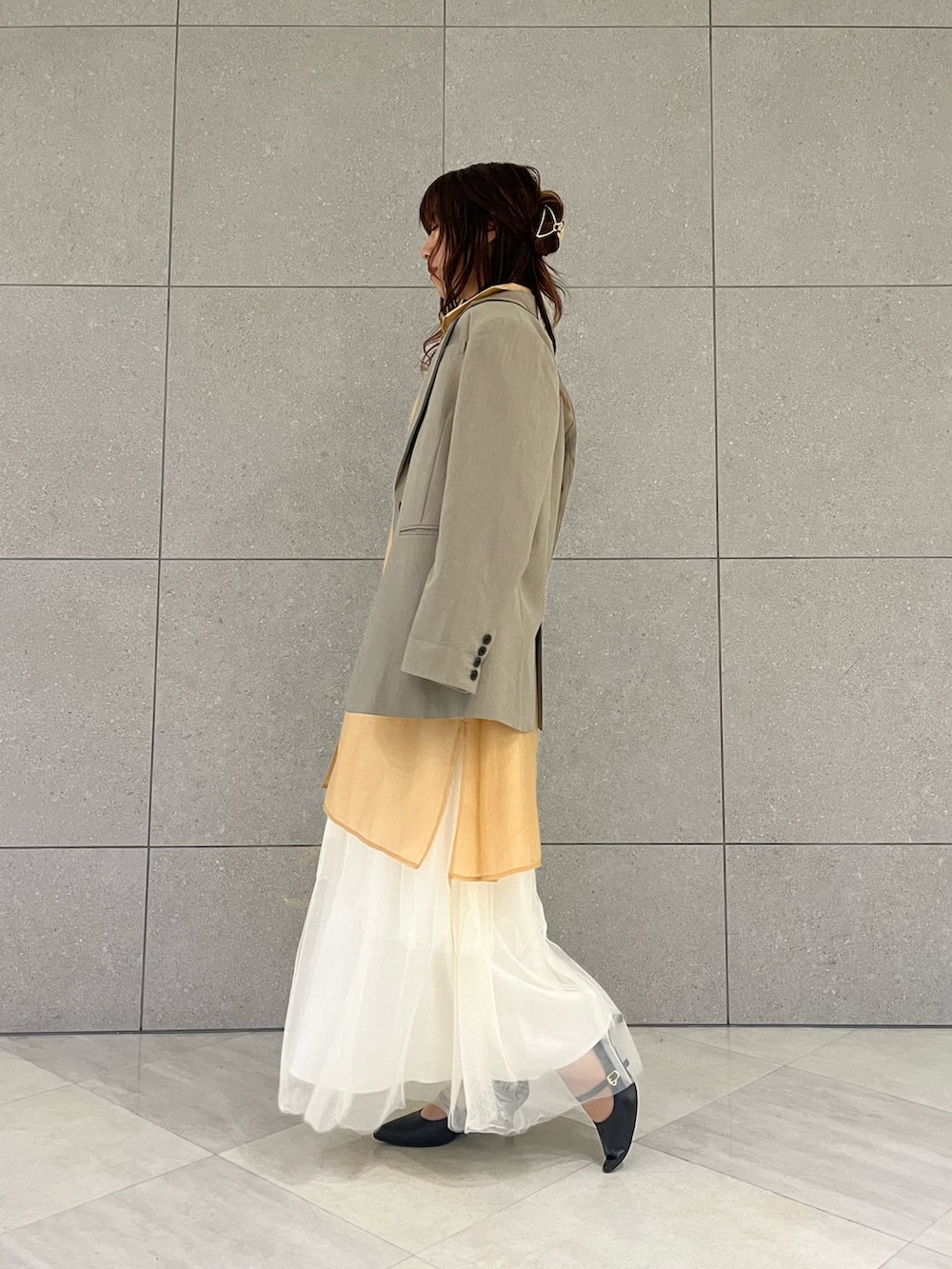 グリーン系のノーカラージャケット、ホワイト系のスカート、オレンジ系のワンピースを着用したレディースの冬コーディネートの3枚目の写真