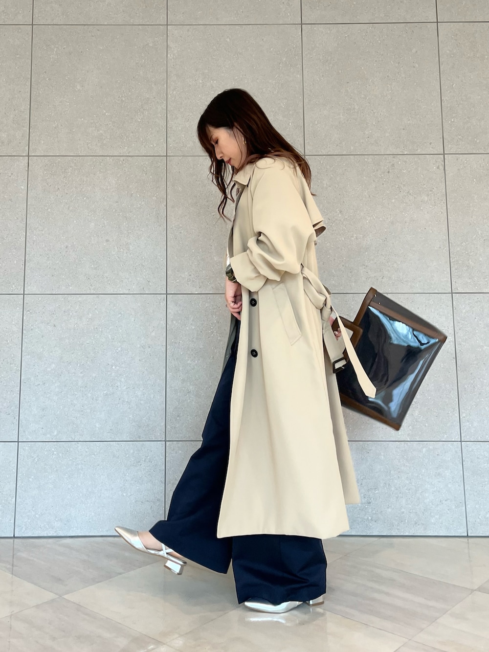 ベージュ系のトレンチコート、ホワイト系のニット/セーター、ブルー系のハンドバッグを着用したレディースの春コーディネートの2枚目の写真