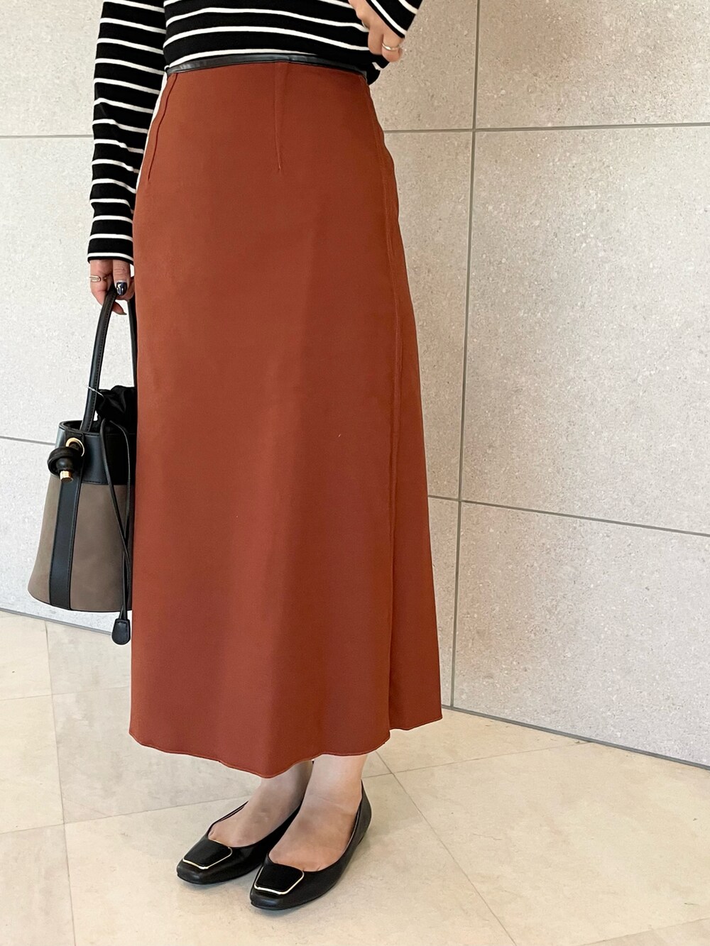 ホワイト系のニット/セーター、ブラック系のスカート、ブラウン系のハンドバッグを着用したレディースの秋コーディネートの4枚目の写真