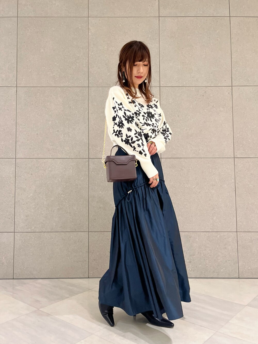 ホワイト系のニット/セーター、グリーン系のスカート、ブラック系のブーツを着用したレディースの冬コーディネートの2枚目の写真