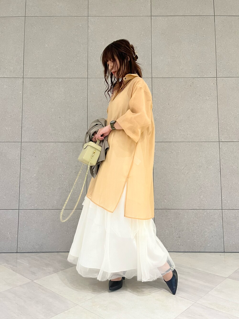 グリーン系のノーカラージャケット、ホワイト系のスカート、オレンジ系のワンピースを着用したレディースの冬コーディネートの4枚目の写真
