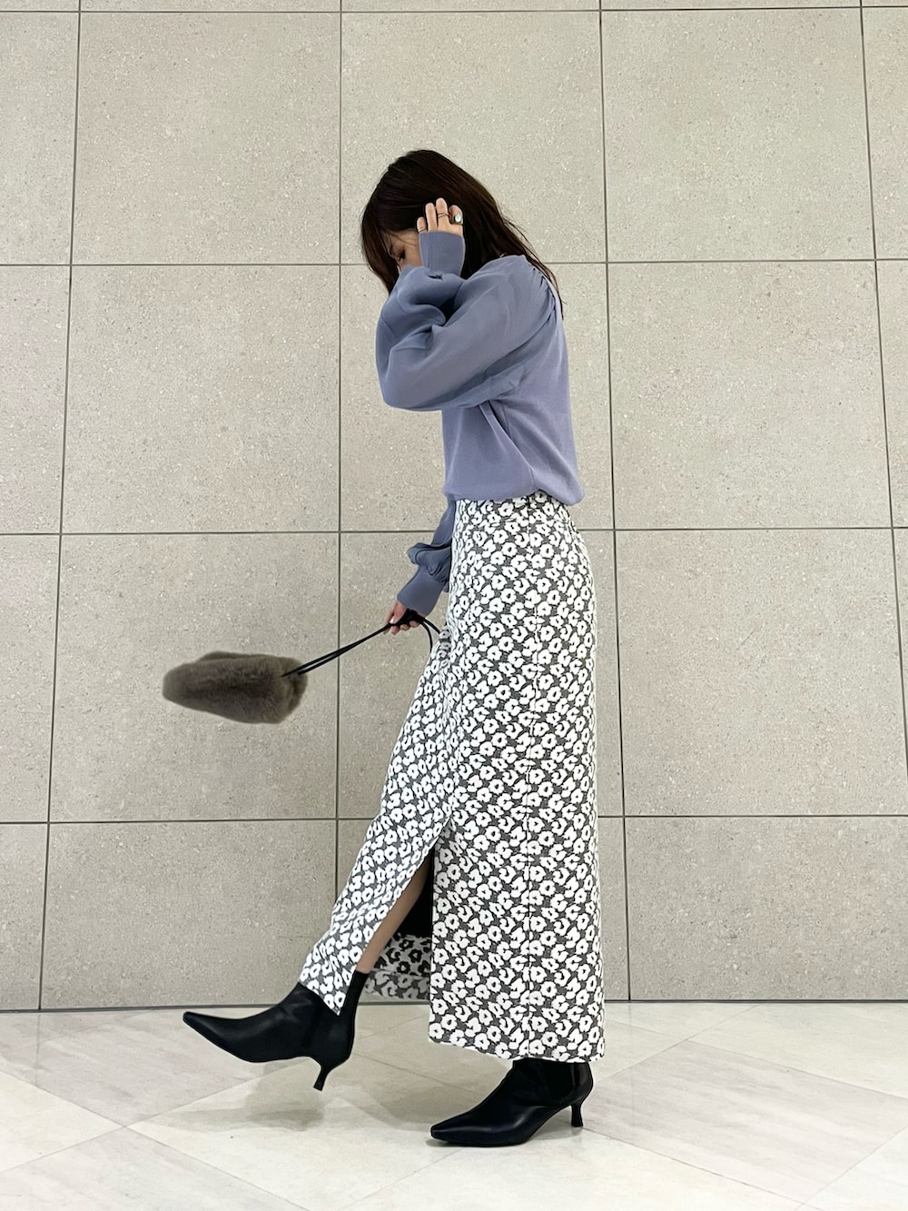 ブルー系のニット/セーター、グレー系のスカート、ブラウン系のハンドバッグを着用したレディースの秋コーディネートの3枚目の写真