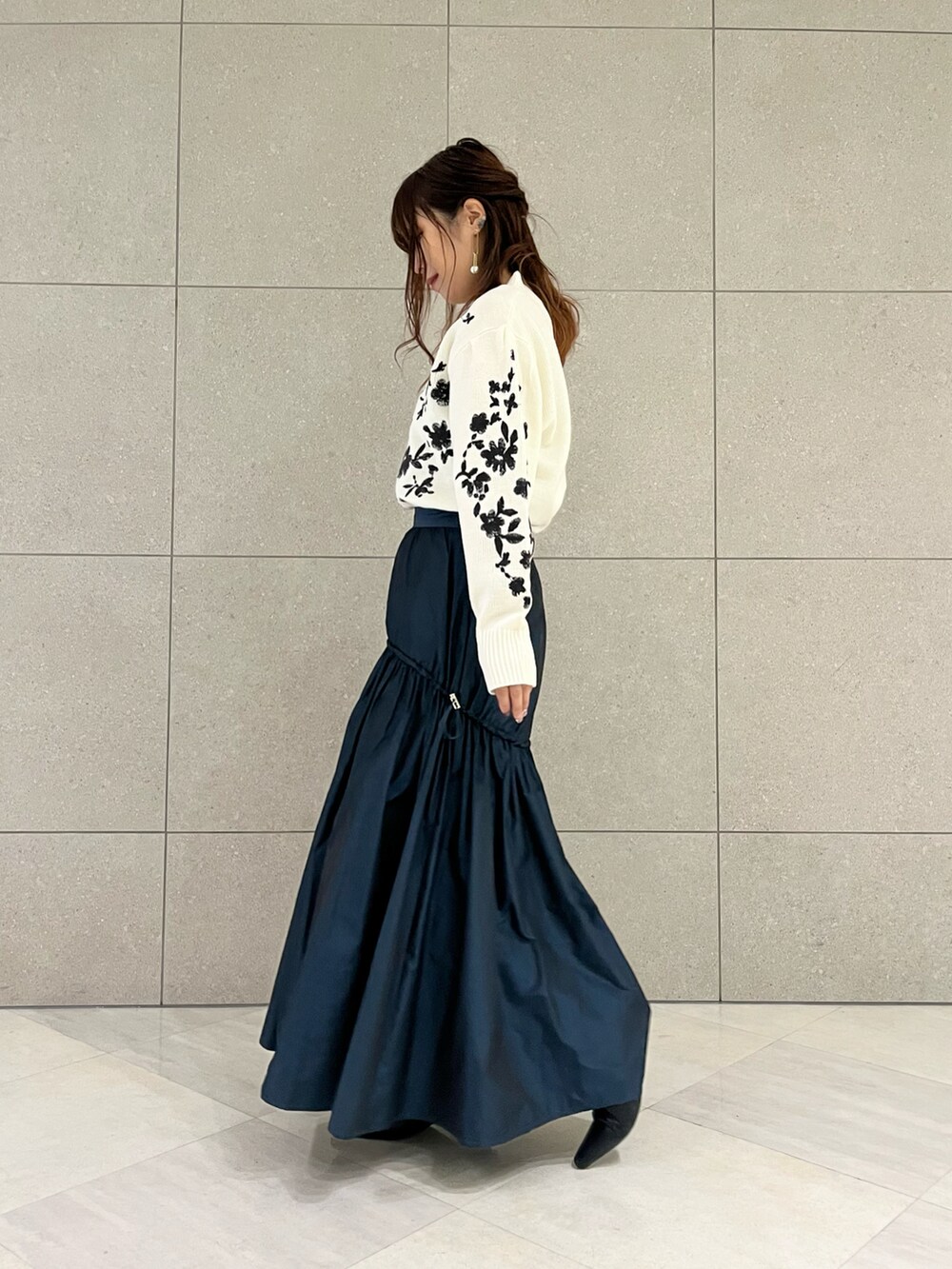 ホワイト系のニット/セーター、グリーン系のスカート、ブラック系のブーツを着用したレディースの冬コーディネートの3枚目の写真