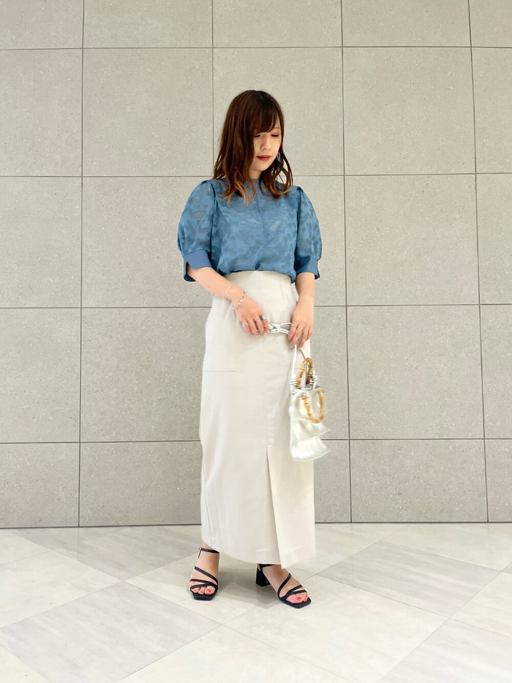 ブルー系のシャツ/ブラウス、ベージュ系のスカート、シルバー系のハンドバッグを着用したレディースの夏コーディネートの2枚目の写真