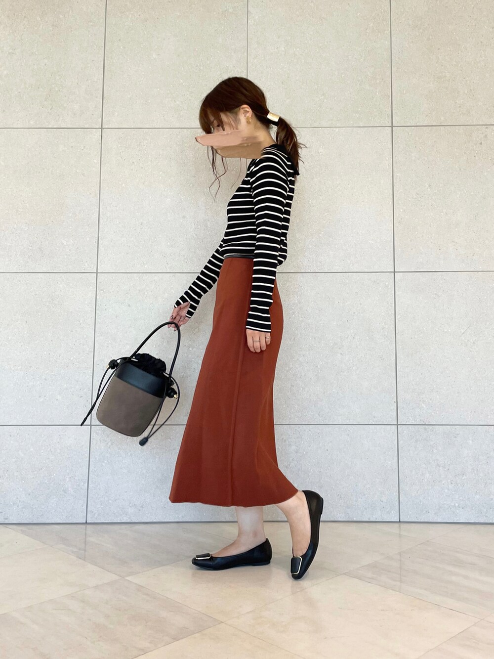 ホワイト系のニット/セーター、ブラック系のスカート、ブラウン系のハンドバッグを着用したレディースの秋コーディネートの2枚目の写真