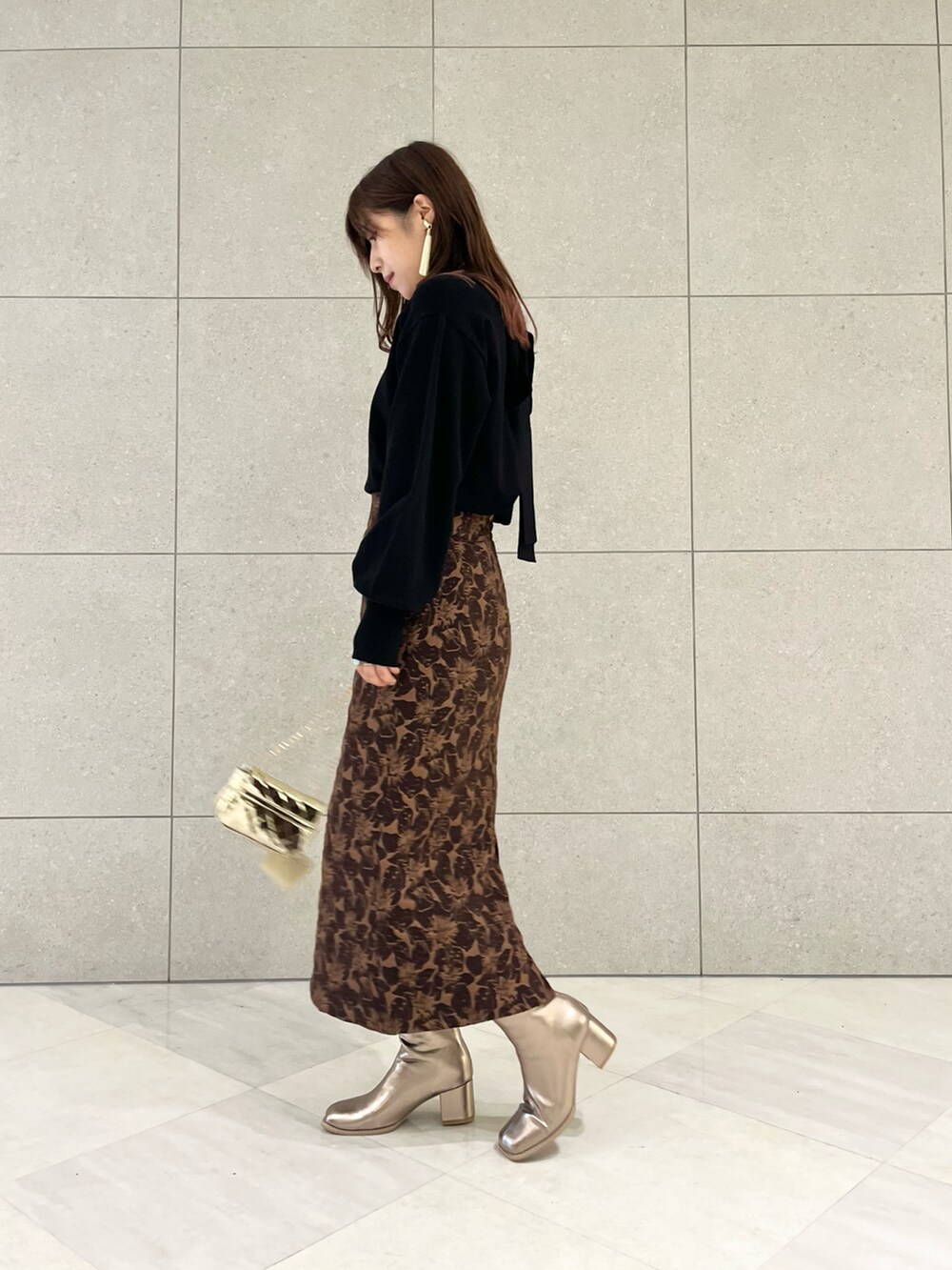 ブラック系のニット/セーター、ブラウン系のスカート、ゴールド系のハンドバッグを着用したレディースの秋コーディネートの3枚目の写真