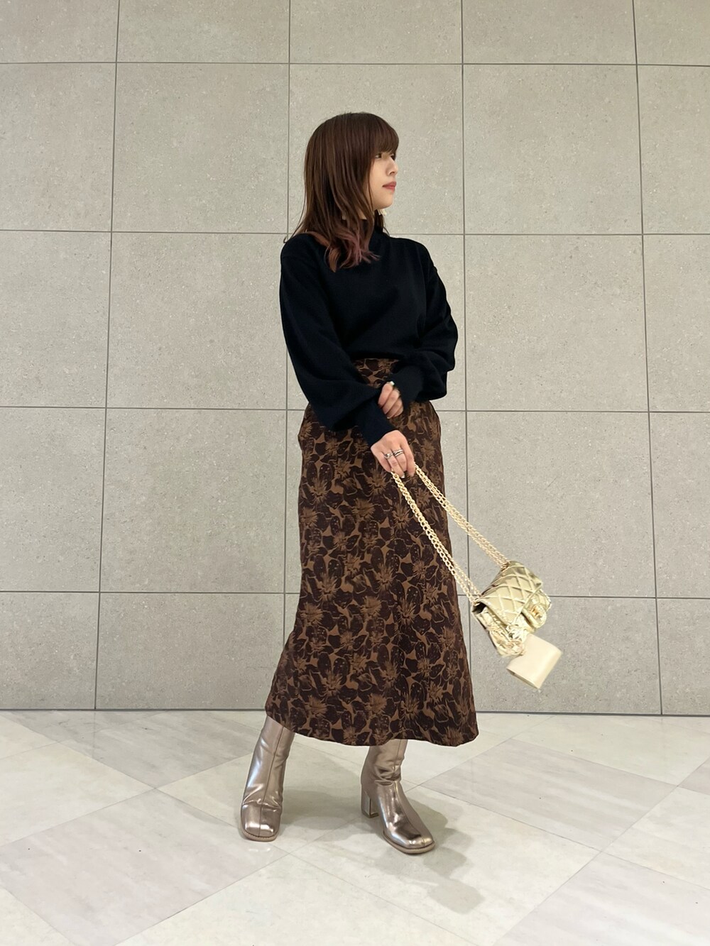 ブラック系のニット/セーター、ブラウン系のスカート、ゴールド系のハンドバッグを着用したレディースの秋コーディネートの2枚目の写真