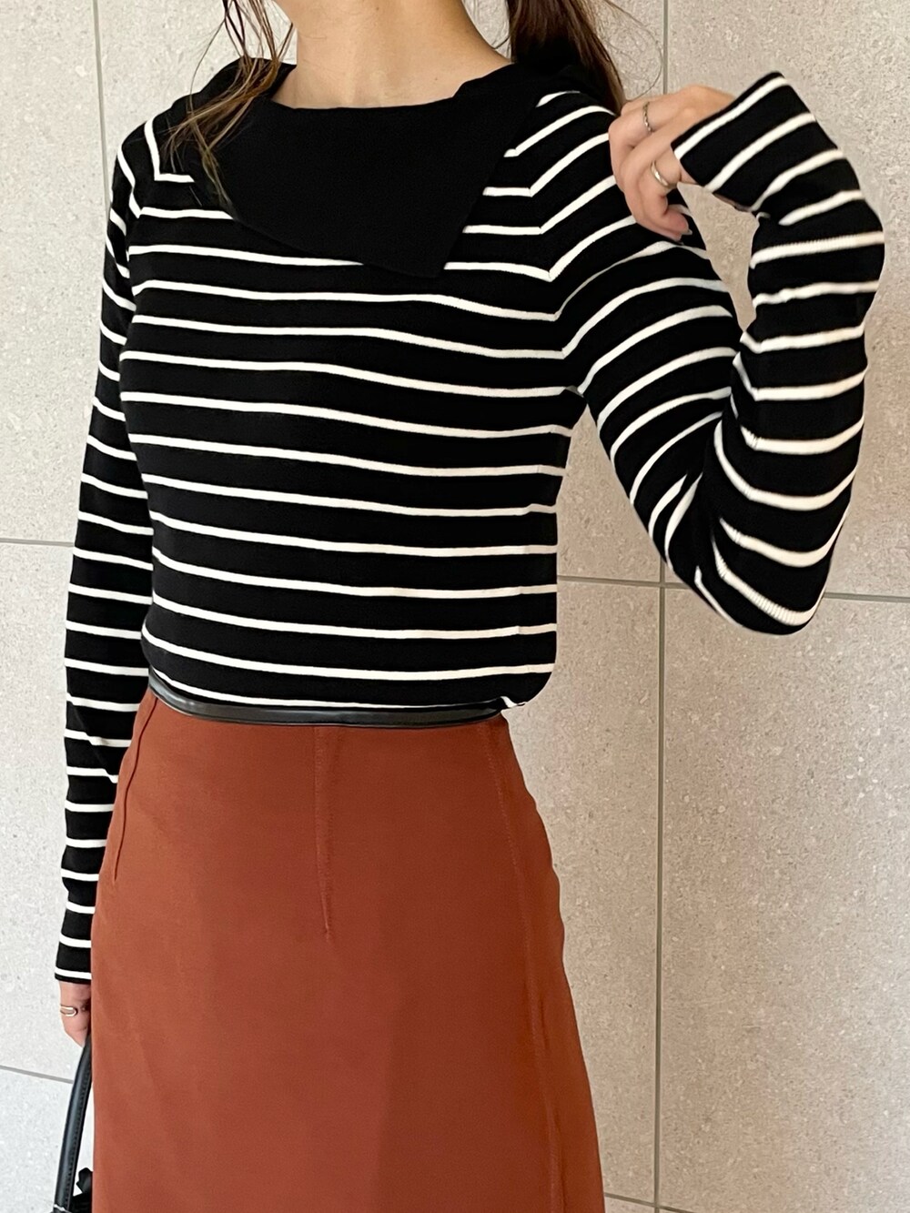 ホワイト系のニット/セーター、ブラック系のスカート、ブラウン系のハンドバッグを着用したレディースの秋コーディネートの3枚目の写真