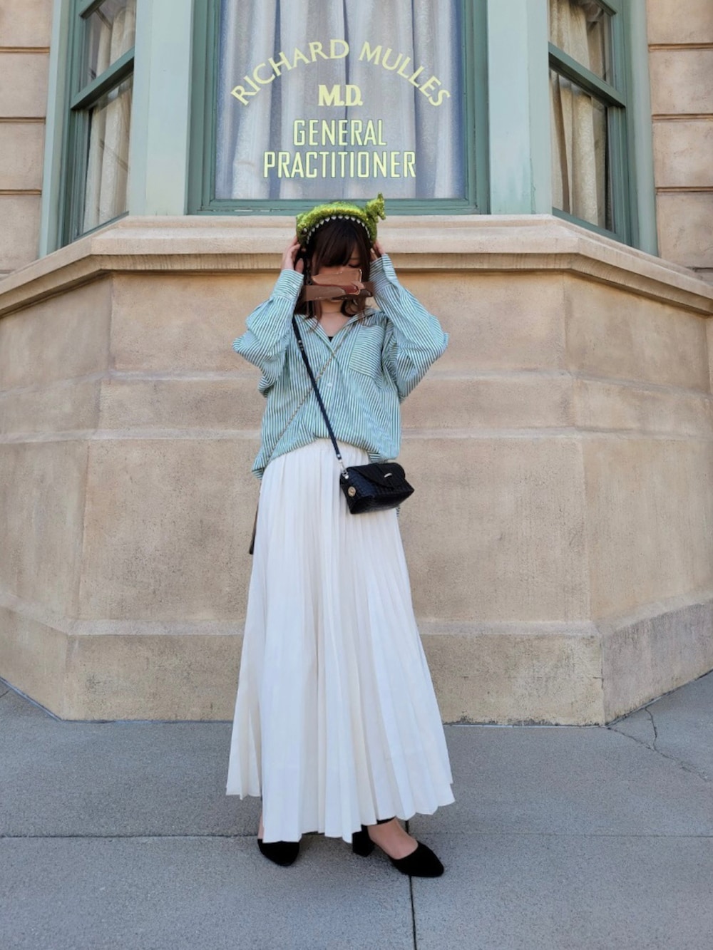 グリーン系のシャツ/ブラウス、ホワイト系のスカート、ブラック系のショルダーバッグを着用したレディースの春コーディネートの2枚目の写真