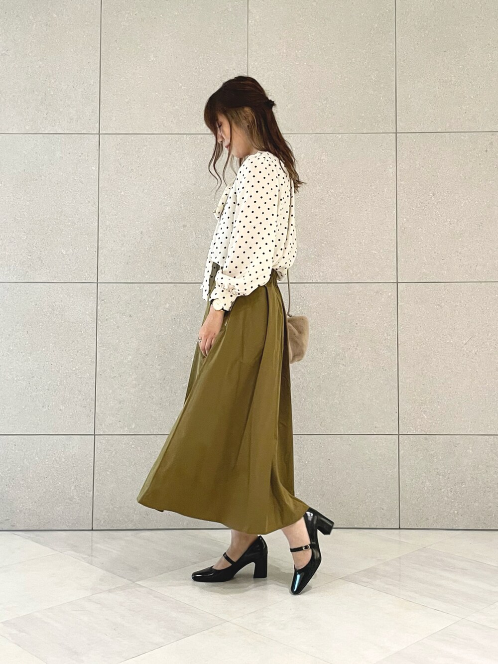 ホワイト系のシャツ/ブラウス、ブラウン系のスカート、ベージュ系のハンドバッグを着用したレディースの秋コーディネートの2枚目の写真