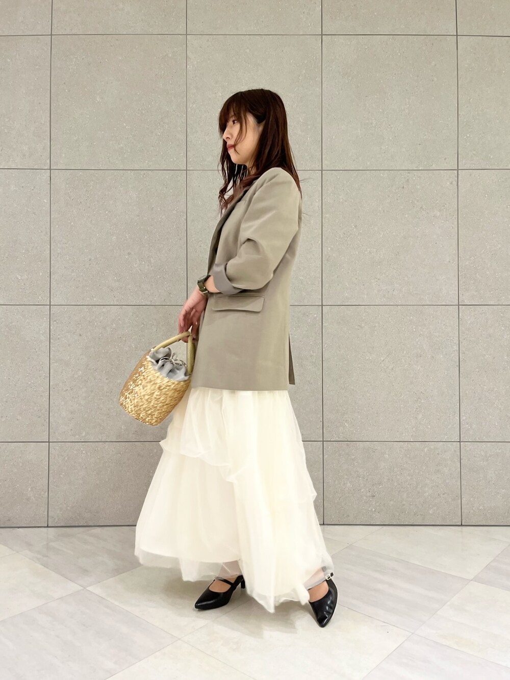 ホワイト系のスカート、ゴールド系のハンドバッグ、ブラック系のパンプスを着用したレディースの冬コーディネートの2枚目の写真