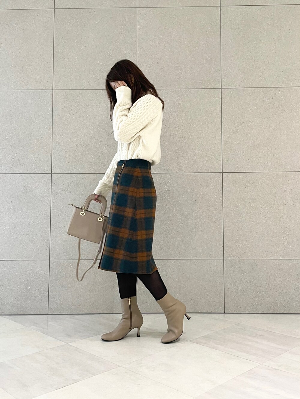 ブラウン系のブーツ、ホワイト系のニット/セーター、オレンジ系のスカートを着用したレディースの秋コーディネートの2枚目の写真
