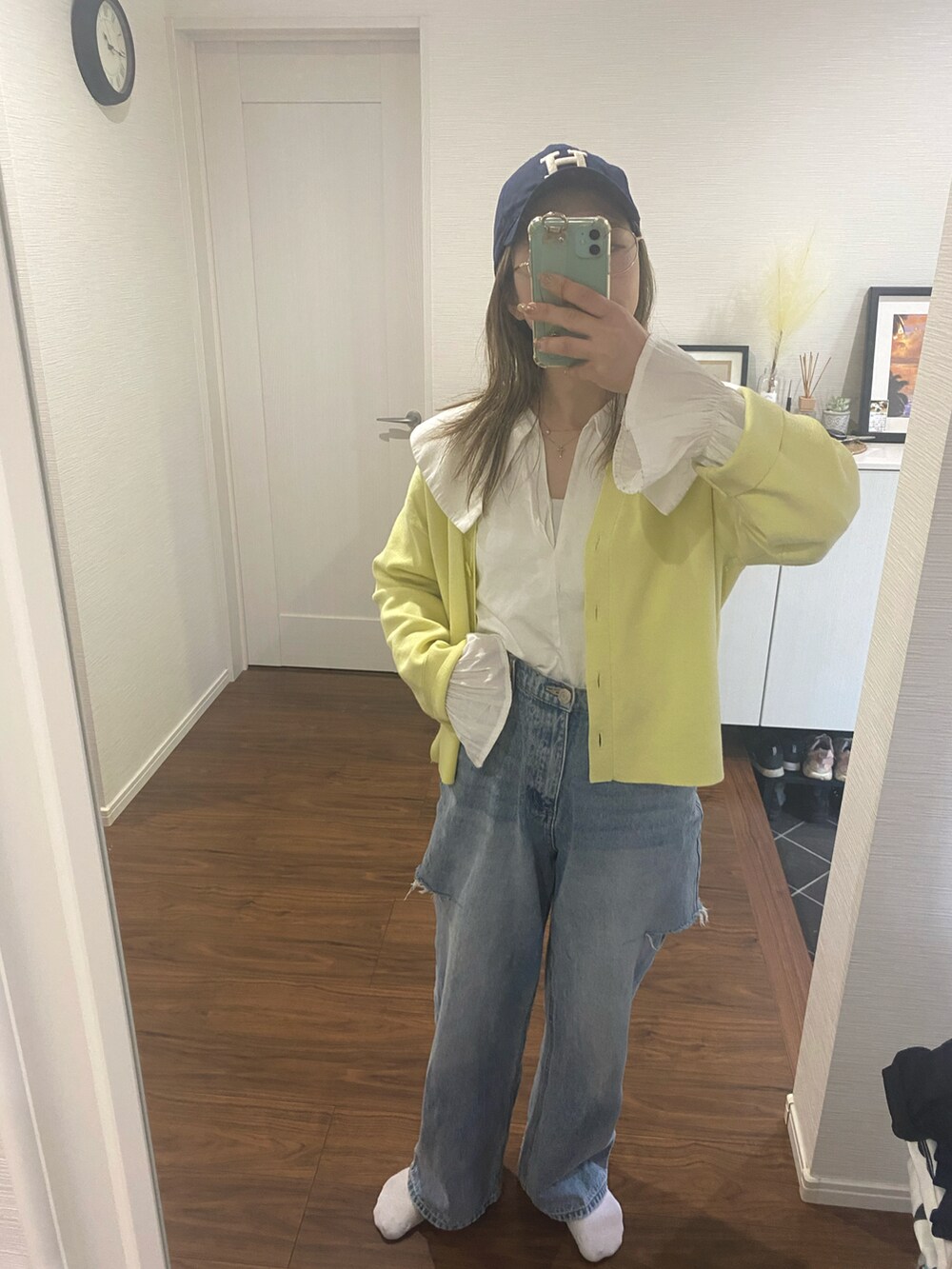 ブルー系のデニムパンツ、イエロー系のカーディガン/ボレロ、ホワイト系のシャツ/ブラウスを着用したレディースの春コーディネートの2枚目の写真