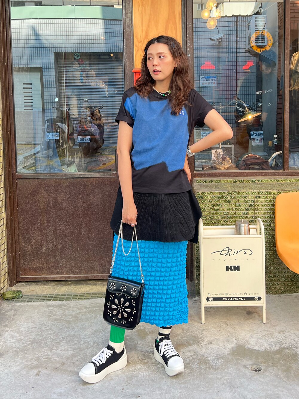 ブラック系のTシャツ/カットソー、ブルー系のスカート、ブラック系のショルダーバッグを着用したレディースの秋コーディネートの2枚目の写真