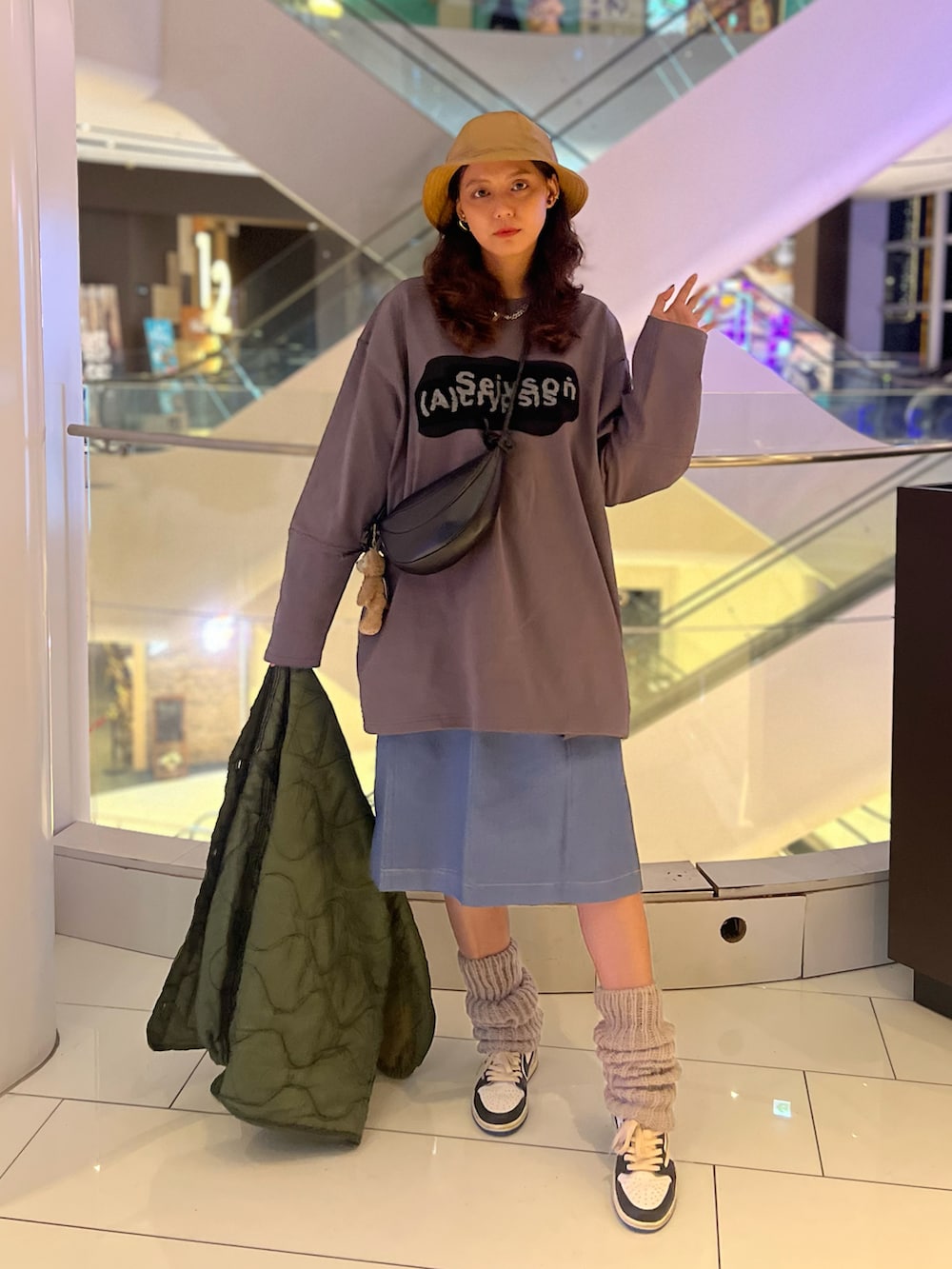 グリーン系のミリタリージャケット、ブルー系のデニムスカート、ブラック系のバッグを着用したレディースの冬コーディネートの2枚目の写真