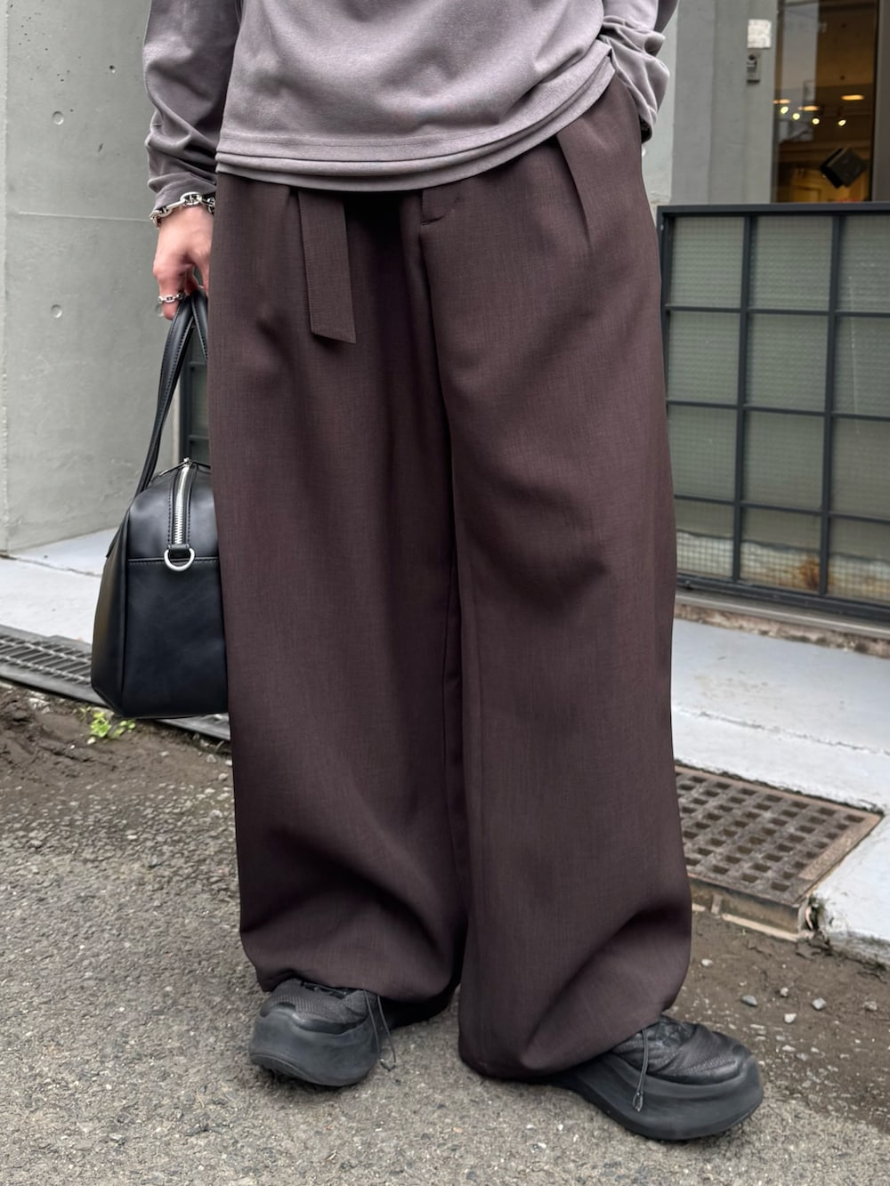 グレー系のスラックス、グレー系のTシャツ/カットソー、ブラック系のショルダーバッグを着用したメンズの春コーディネートの6枚目の写真