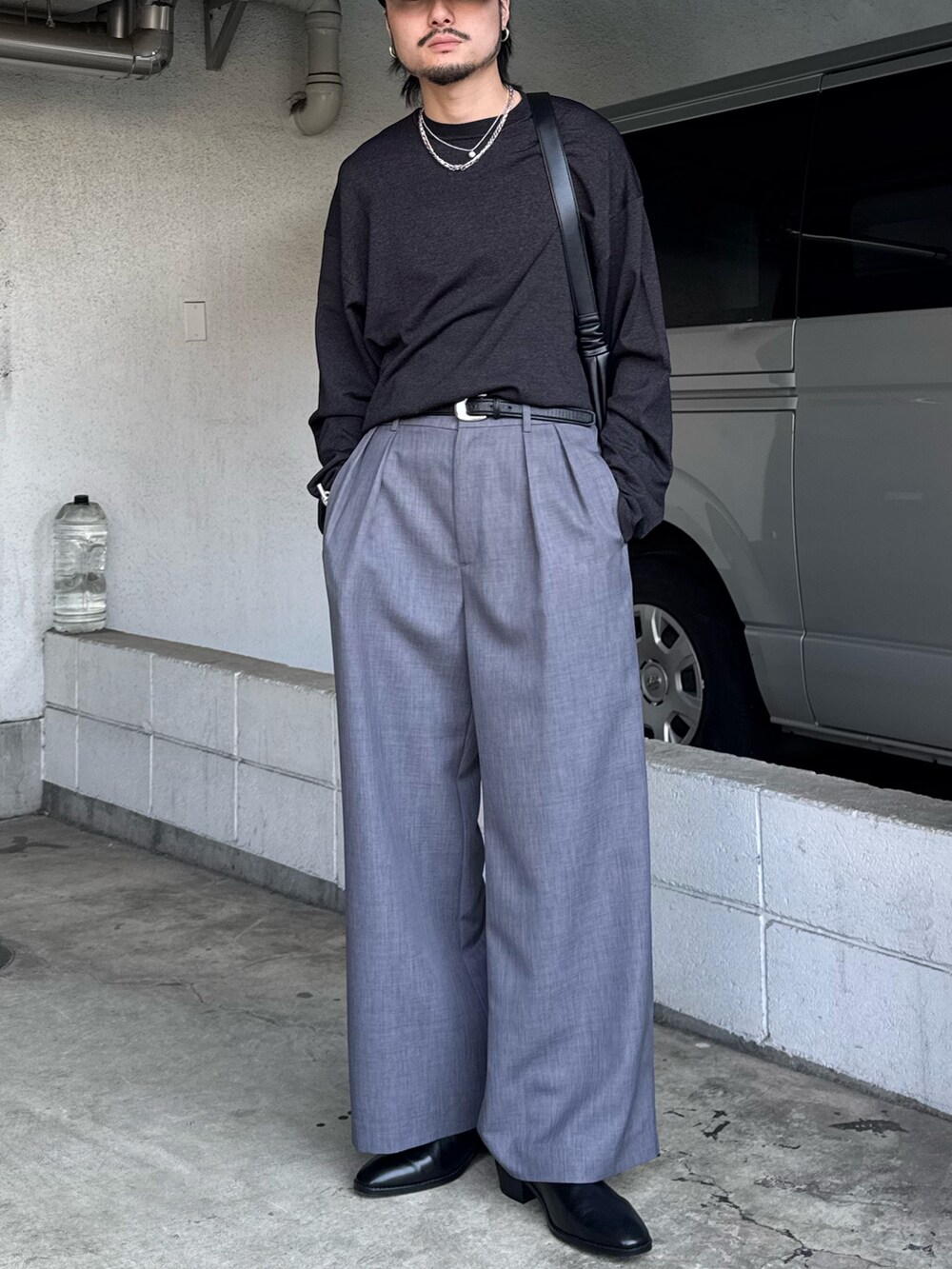 ブラック系のニット/セーター、グレー系のスラックス、ブラック系のショルダーバッグを着用したメンズの春コーディネートの2枚目の写真