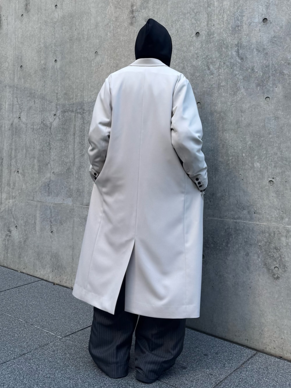 グレー系のチェスターコート、ブルー系のデニムジャケット、ブラック系のパーカーを着用したメンズの冬コーディネートの4枚目の写真