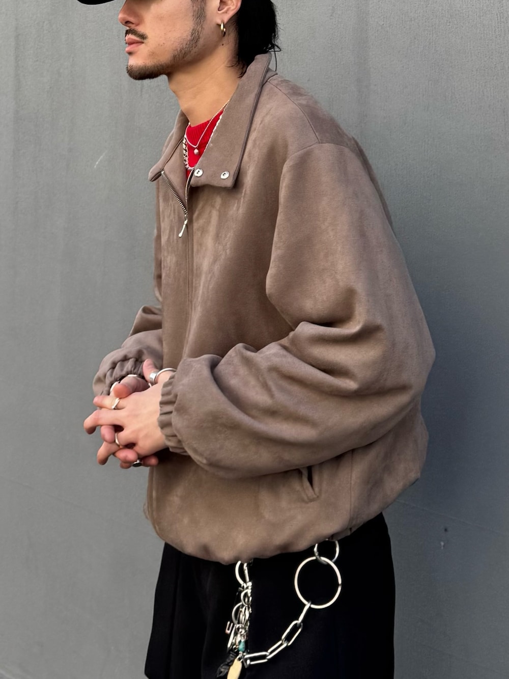 レッド系のニット/セーター、グレー系のブルゾン、ブラック系のスラックスを着用したメンズの冬コーディネートの6枚目の写真