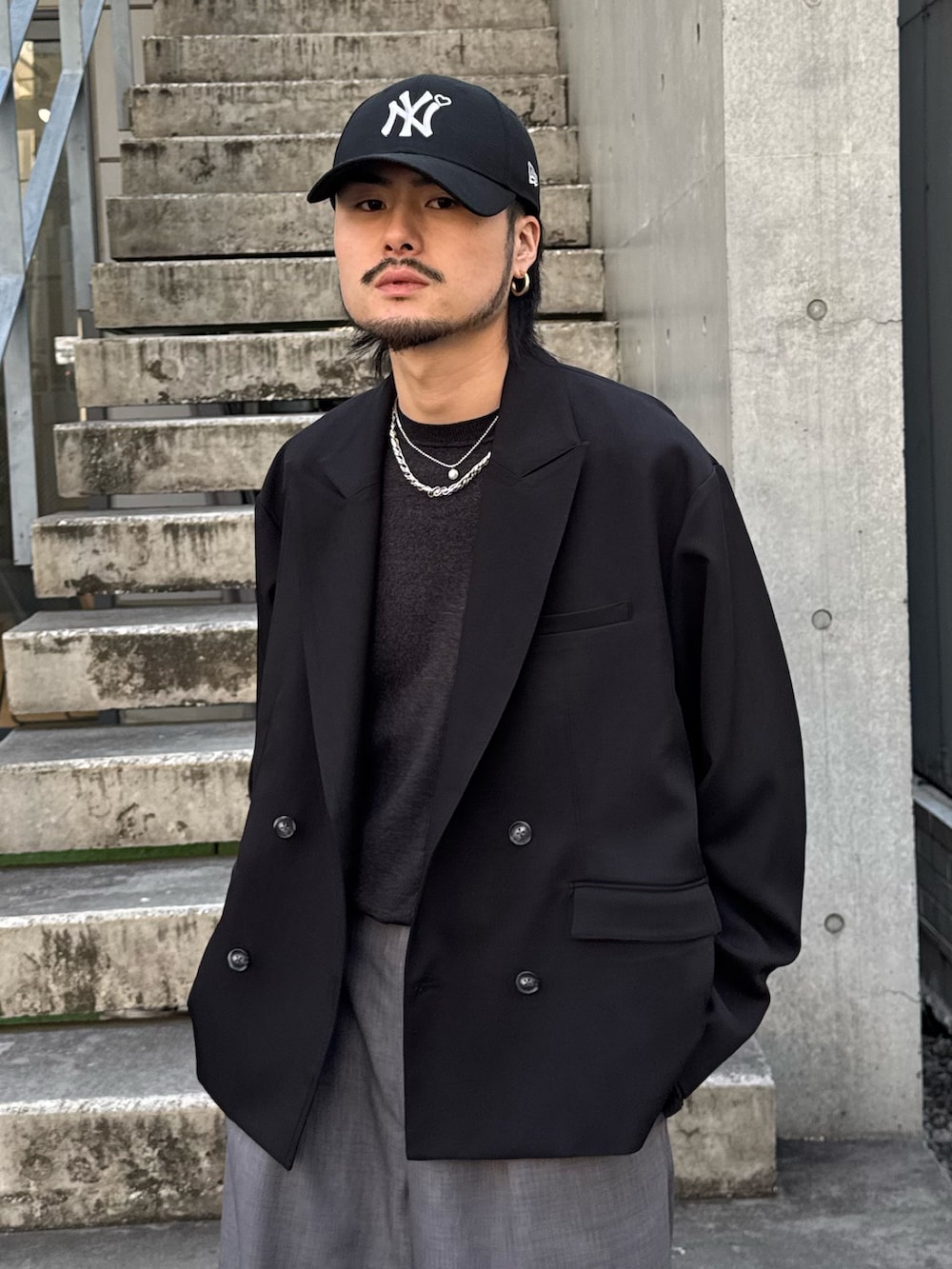 ブラック系のテーラードジャケット、ブラック系のニット/セーター、グレー系のスラックスを着用したメンズの春コーディネートの3枚目の写真