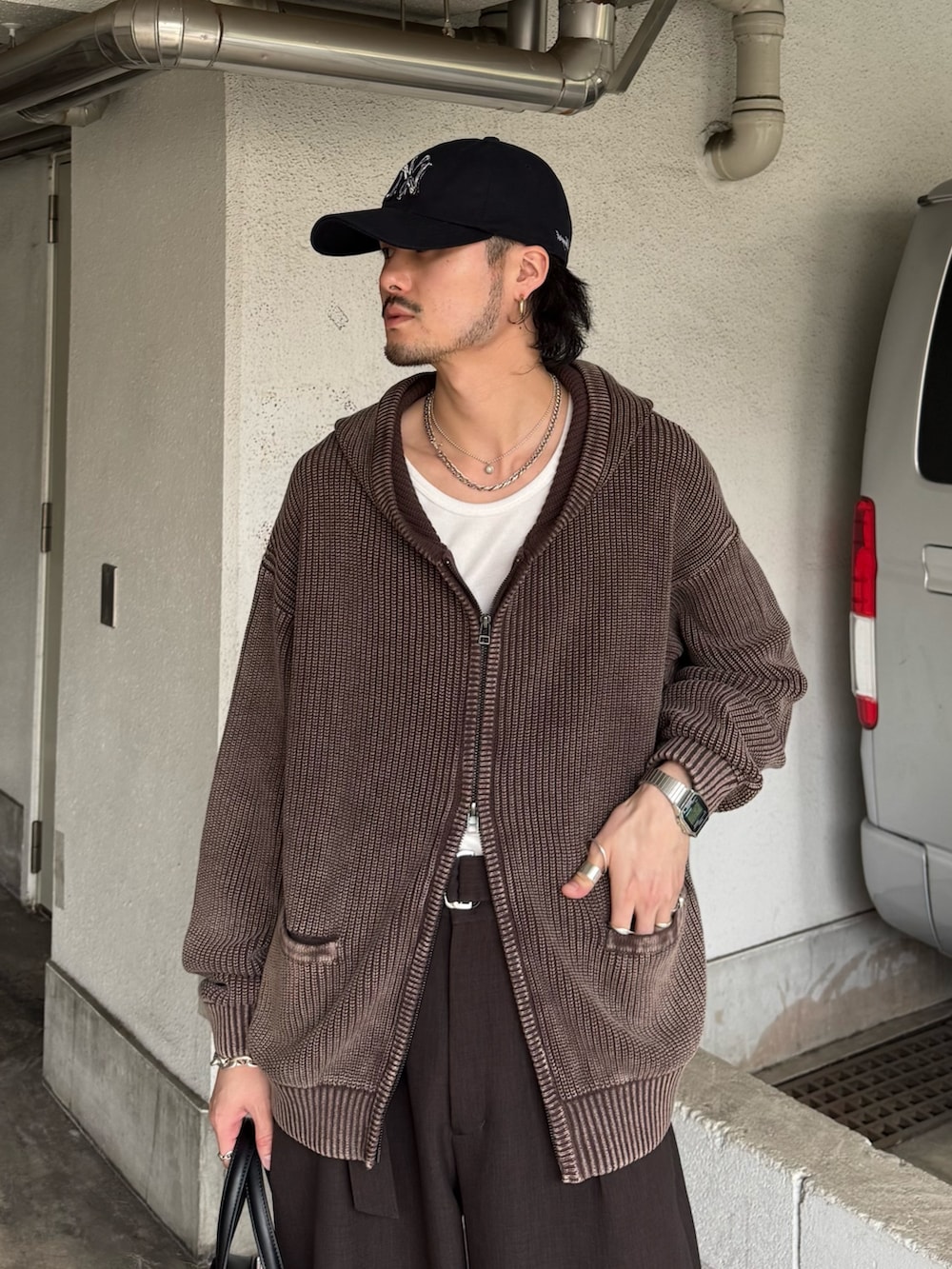 ブラウン系のパーカー、グレー系のスラックス、ブラック系のショルダーバッグを着用したメンズの春コーディネートの6枚目の写真