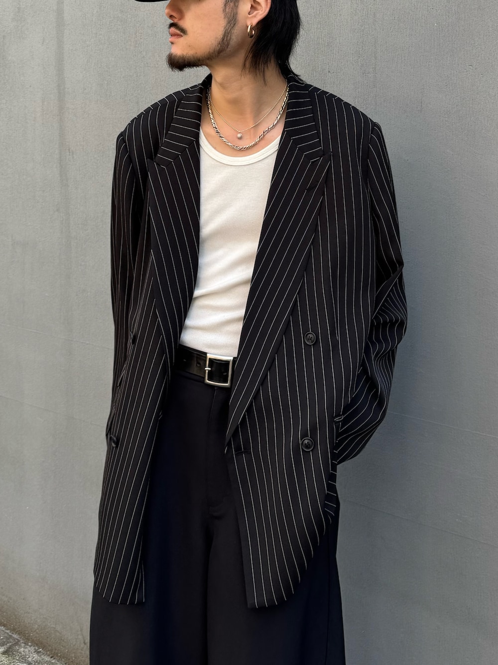 ブラック系のスラックス、ホワイト系のタンクトップ、ブラック系のテーラードジャケットを着用したメンズの春コーディネートの3枚目の写真