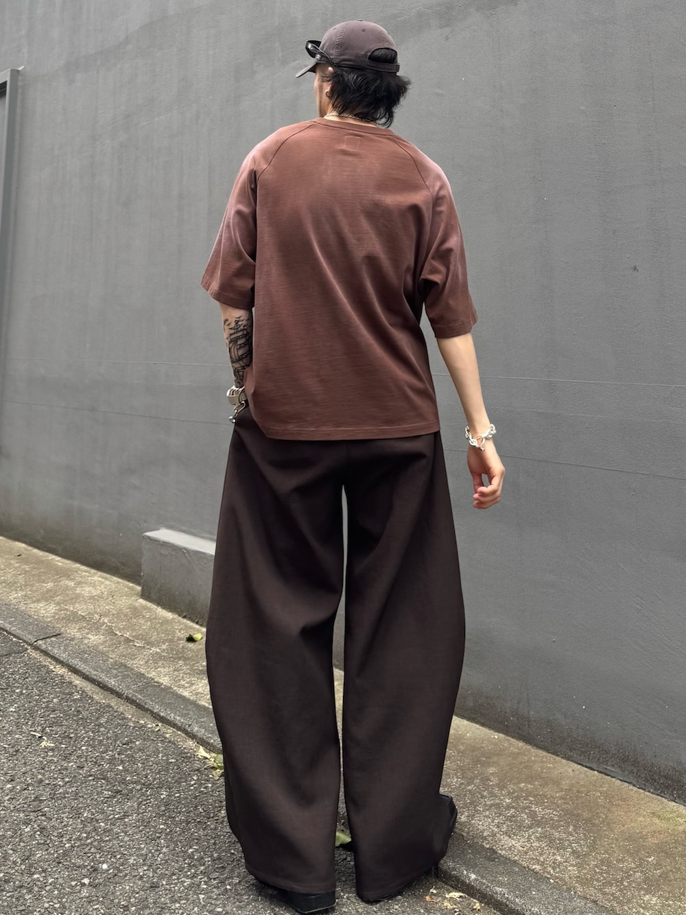 グレー系のスラックス、ブラウン系のTシャツ/カットソーを着用したメンズの夏コーディネートの3枚目の写真