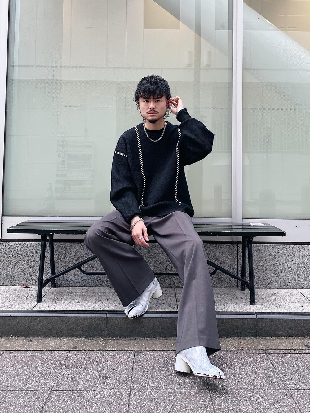 ブラック系のニット/セーター、グレー系のスラックスを着用したメンズの秋コーディネートの2枚目の写真