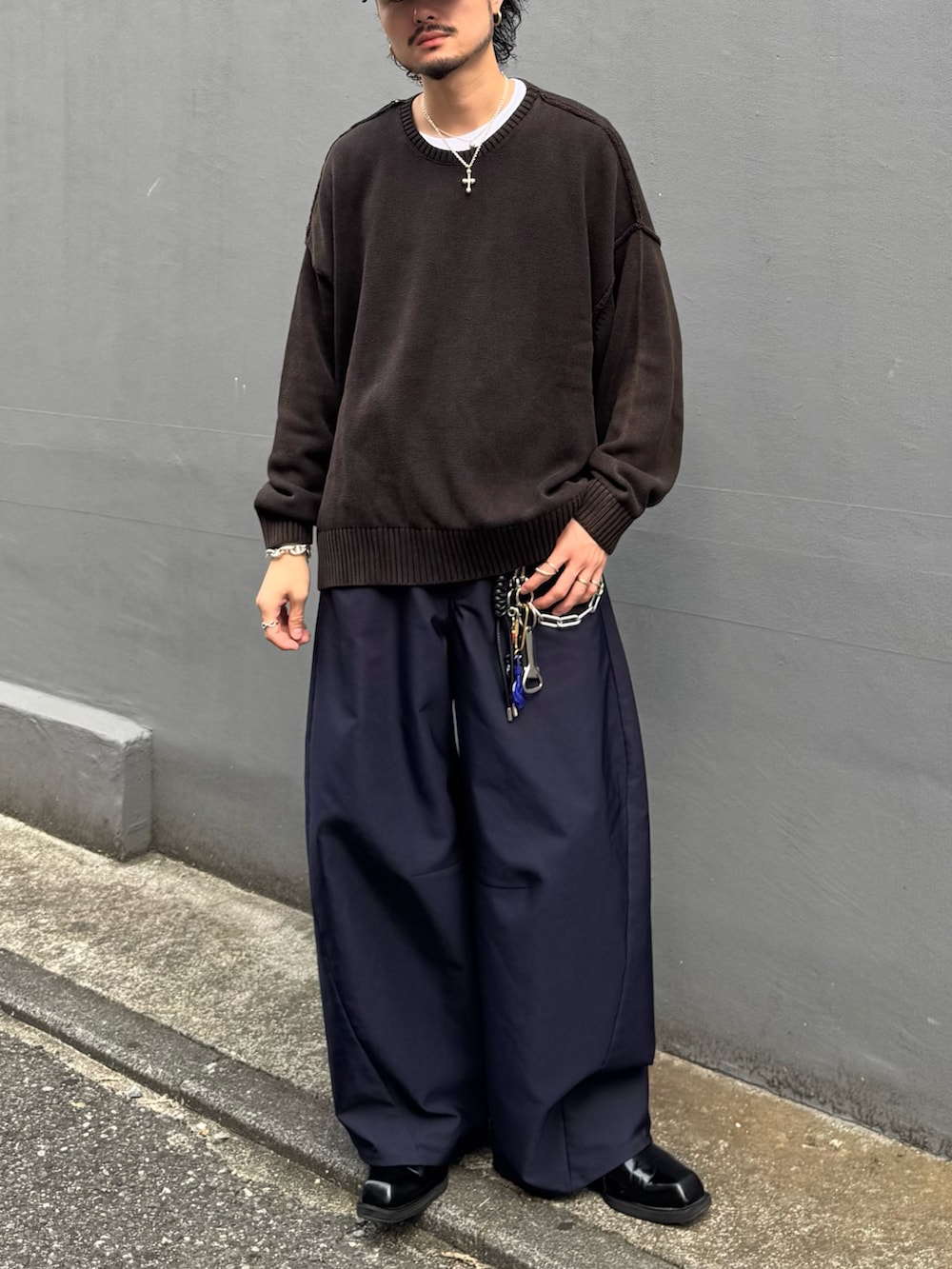 ブラック系のニット/セーター、ブルー系のスラックス、ブルー系のキャップを着用したメンズの秋コーディネートの3枚目の写真