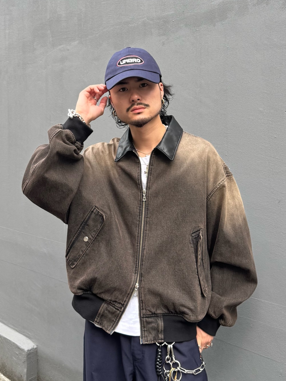 ブラウン系のデニムジャケット、ブルー系のスラックス、ブルー系のキャップを着用したメンズの秋コーディネートの4枚目の写真