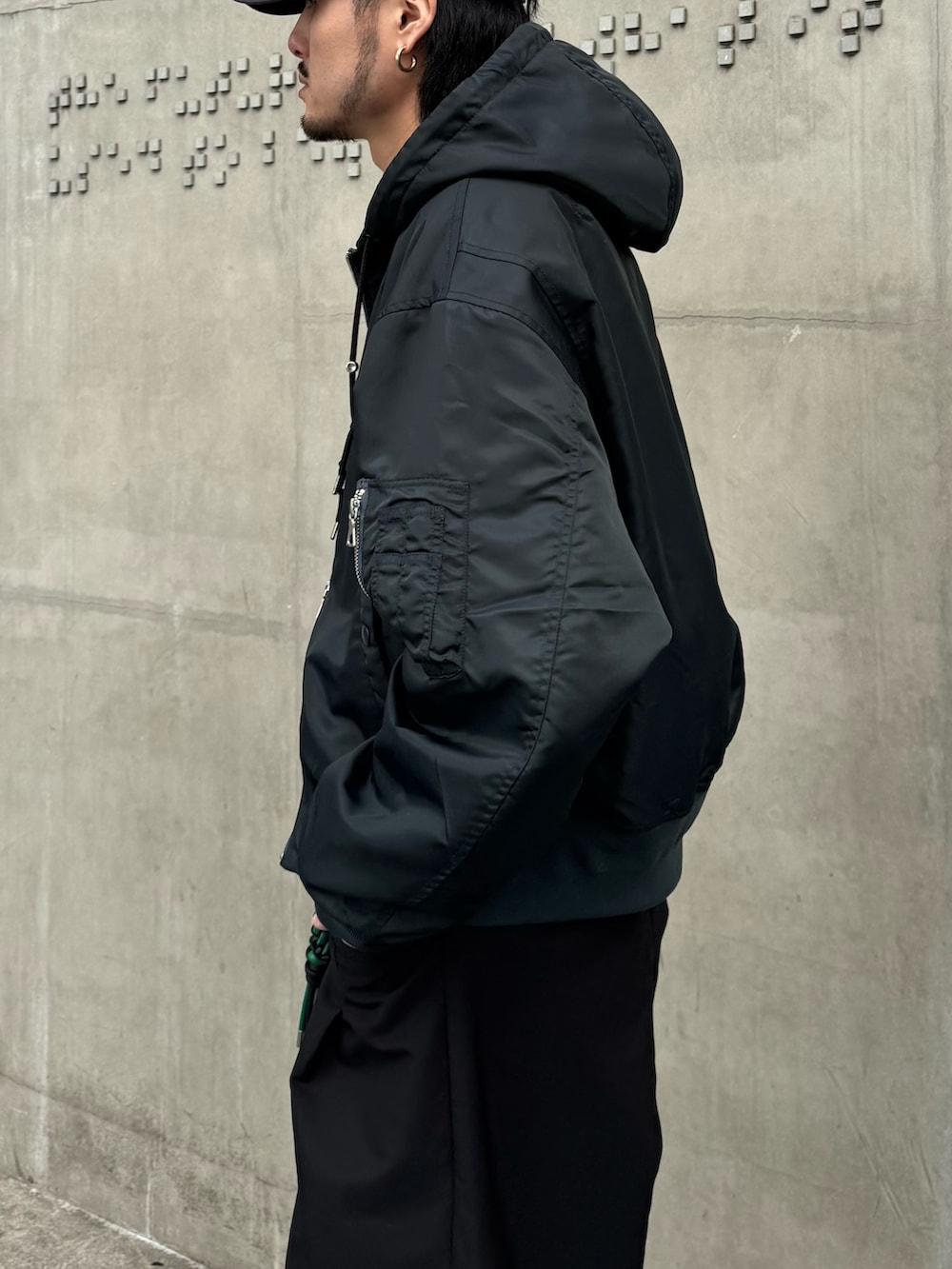 グリーン系のブルゾン、ブラック系のその他パンツ、ブラック系のキーホルダーを着用したメンズの冬コーディネートの7枚目の写真