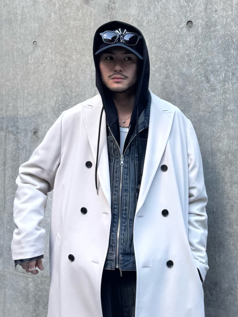 グレー系のチェスターコート、ブルー系のデニムジャケット、ブラック系のパーカーを着用したメンズの冬コーディネートの8枚目の写真