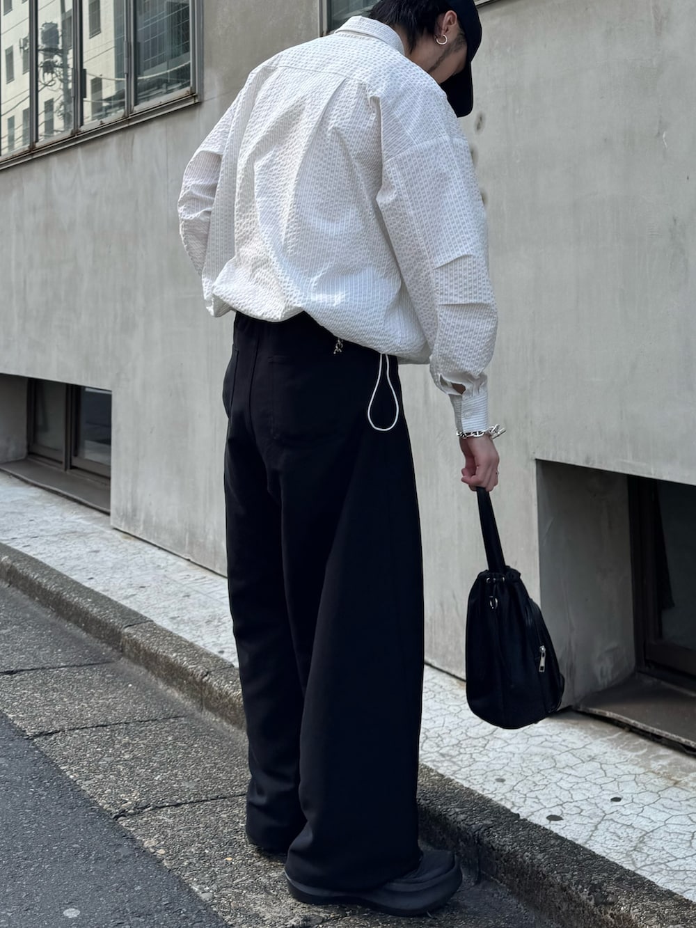 ホワイト系のシャツ/ブラウス、ブラック系のショルダーバッグ、ブラック系のスラックスを着用したメンズの春コーディネートの2枚目の写真