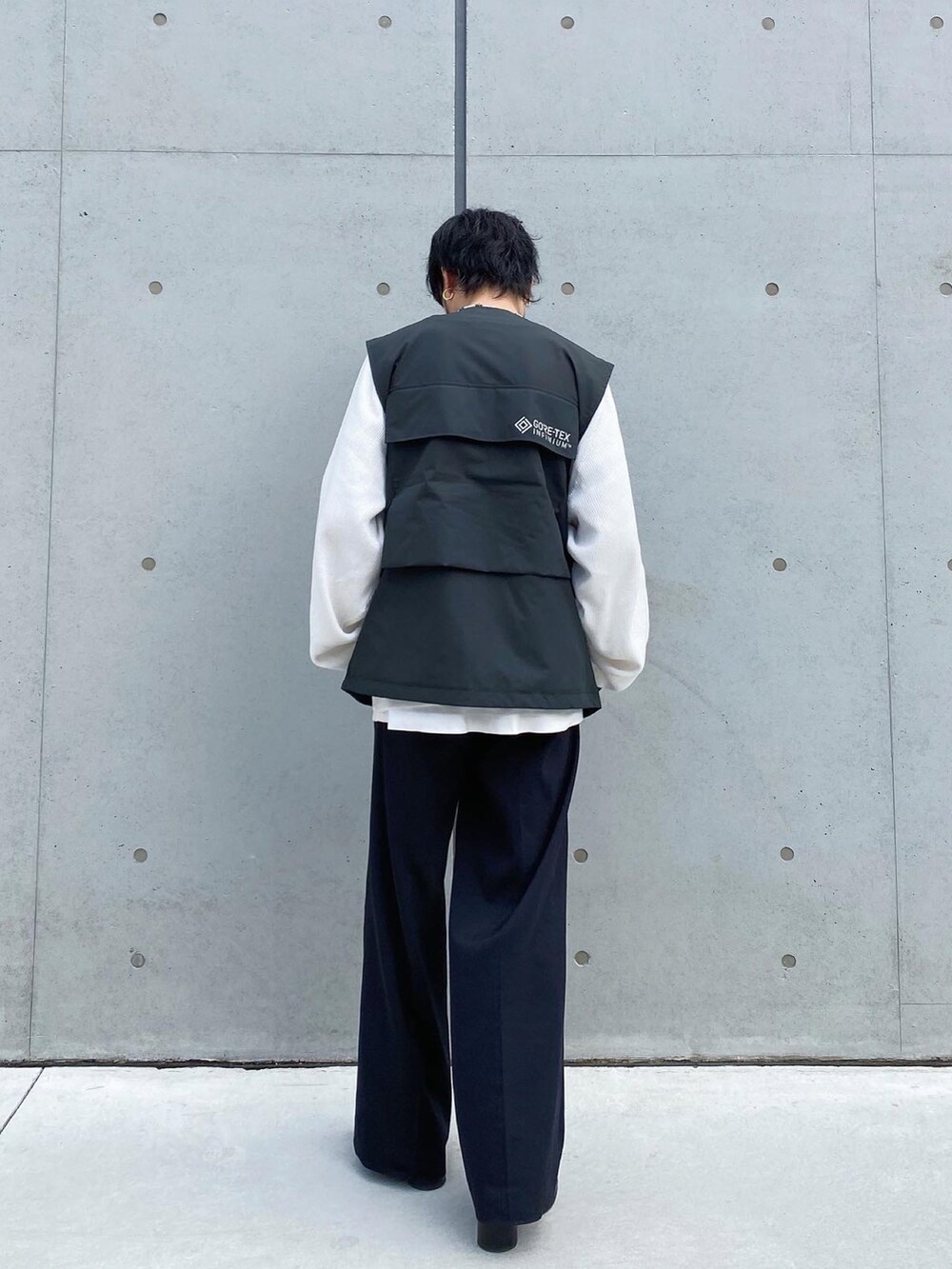 ブラック系のベスト、ブラック系のスラックス、ブラック系のブーツを着用したメンズの冬コーディネートの3枚目の写真