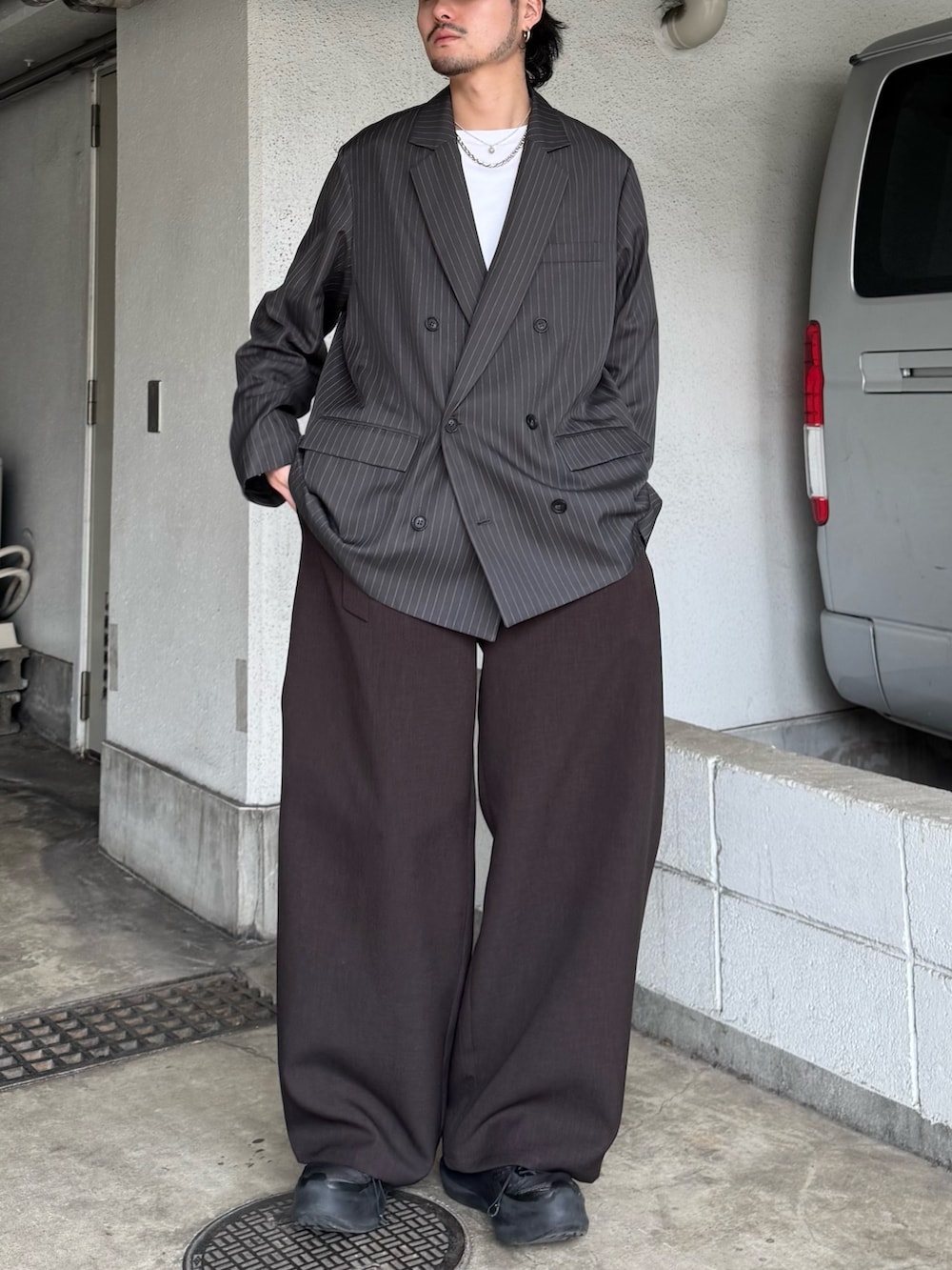 グレー系のテーラードジャケット、グレー系のスラックス、ホワイト系のTシャツ/カットソーを着用したメンズの春コーディネートの3枚目の写真