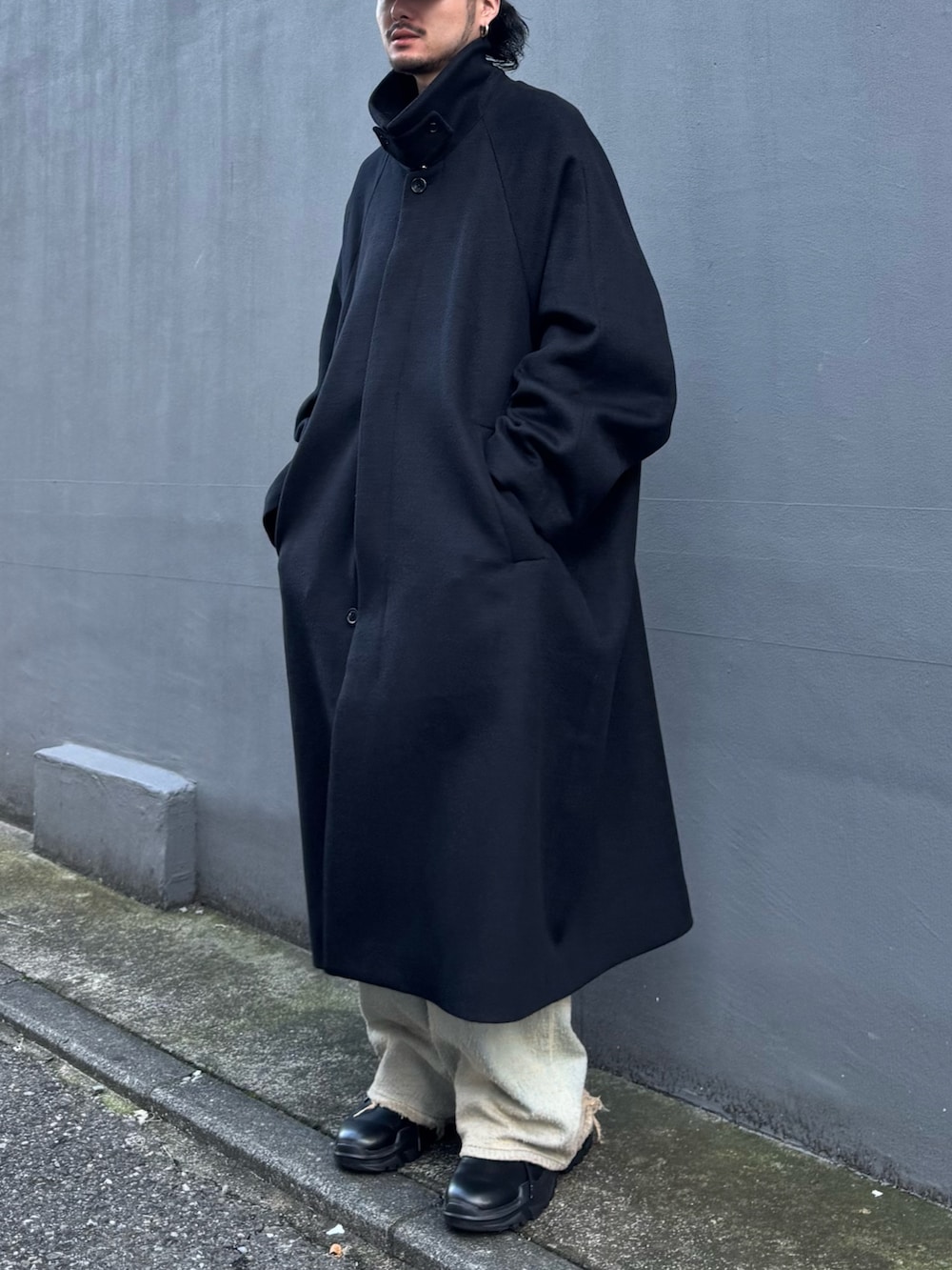 ブルー系のニット/セーター、ブルー系のデニムパンツ、ブラック系のステンカラーコートを着用したメンズの秋コーディネートの5枚目の写真