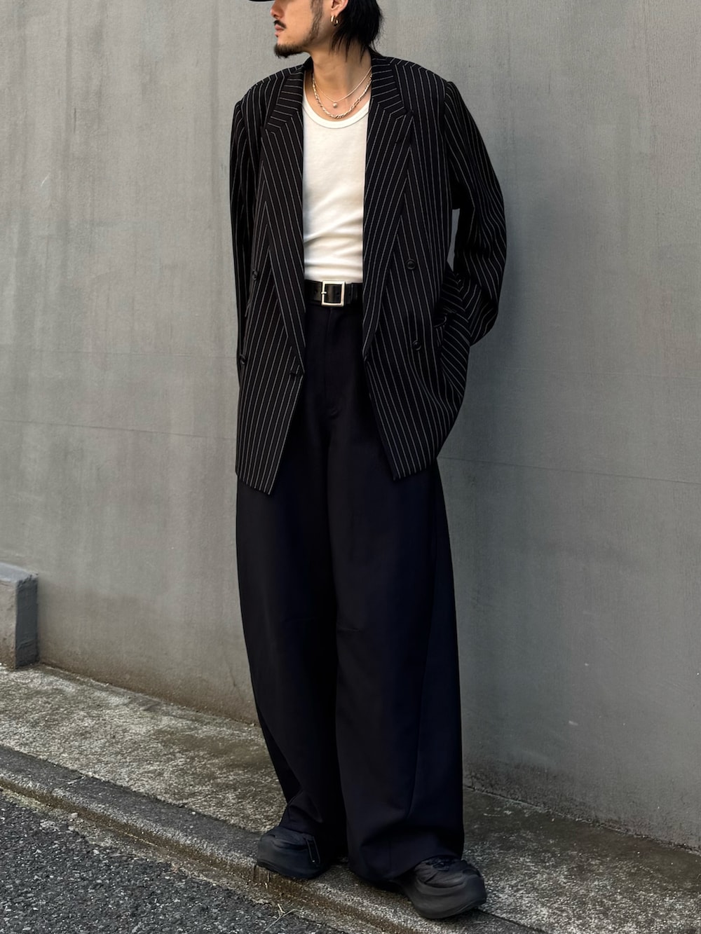 ブラック系のスラックス、ホワイト系のタンクトップ、ブラック系のテーラードジャケットを着用したメンズの春コーディネートの2枚目の写真