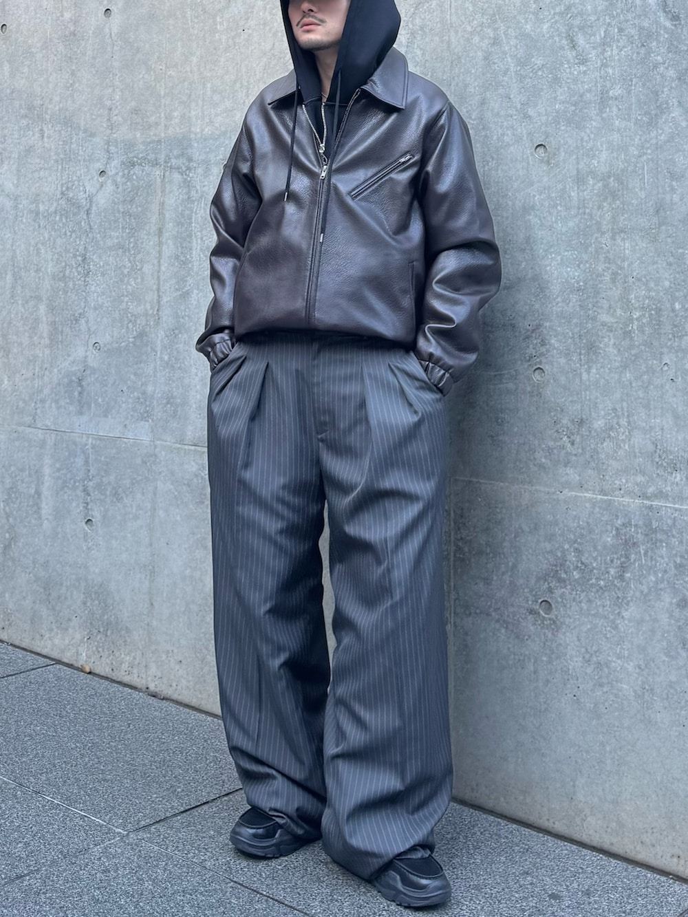 グレー系のスラックス、ブラック系のローファー、ブラック系のパーカーを着用したメンズの冬コーディネートの4枚目の写真