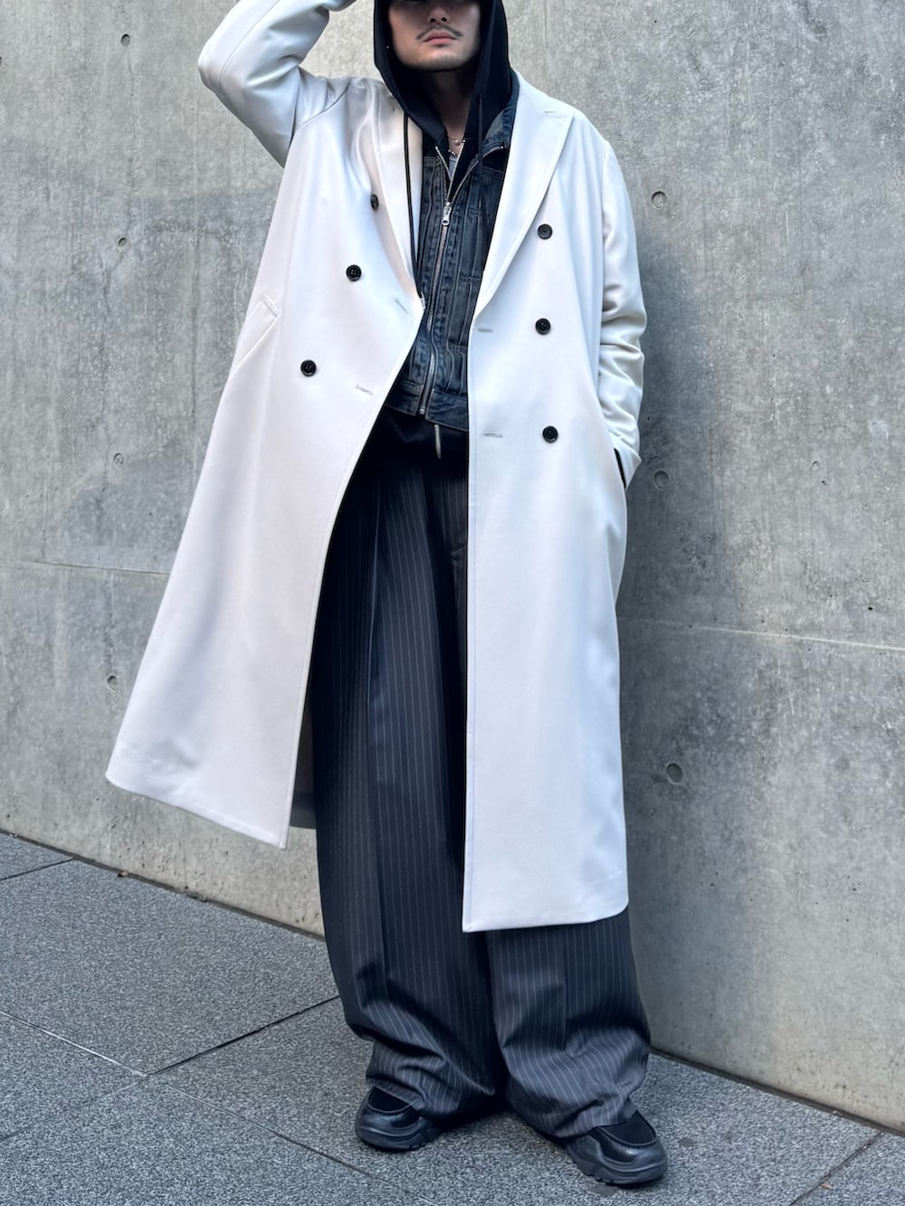 グレー系のチェスターコート、ブルー系のデニムジャケット、ブラック系のパーカーを着用したメンズの冬コーディネートの5枚目の写真