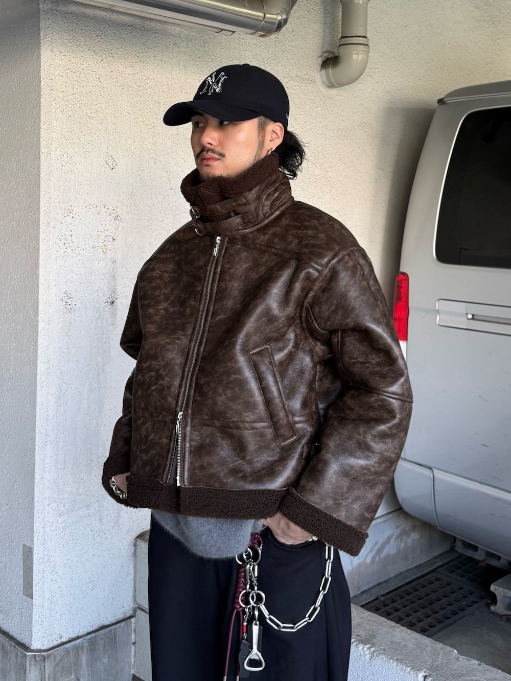 ブラック系のスラックス、グレー系のニット/セーター、ブラウン系のブルゾンを着用したメンズの秋コーディネートの6枚目の写真